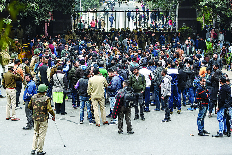 Supporters, students, media representatives and police force stand outside the Jawaharlal Nehru University (JNU) gate in New Delhi on January 6, 2020. - Protests are planned across India on January 6 after a rampage by masked assailants wielding batons and iron rods at a top university left more than two dozen injured. The traditionally left-leaning Jawaharlal Nehru University (JNU) in New Delhi has become a hotbed of protest after a new citizenship bill was brought in that critics say is anti-Muslim. (Photo by Money SHARMA / AFP)