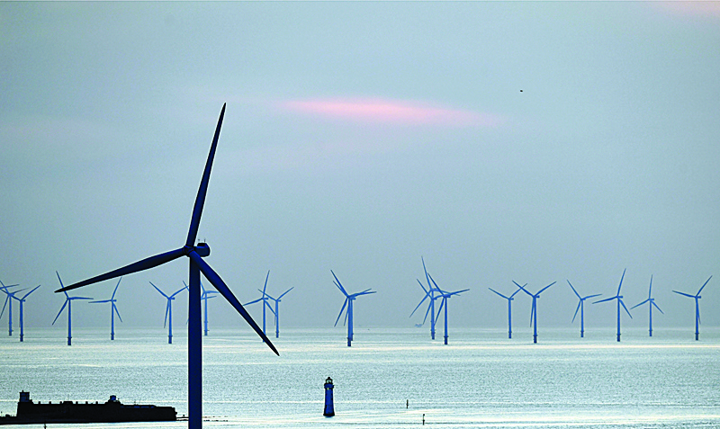 (FILES) In this file photo taken on May 14, 2019 New Brighton lighthouse is pictured at sunset, in New Brighton, at the mouth of the river Mersey, in north-west England on May 14, 2019, with the Burbo Bank Offshore Wind Farm visible on the horizon. - Britain, a global leader in offshore wind energy, plans to make the sector one of the pillars of its transition to carbon neutrality in the coming decades. The country aims to quadruple its offshore electricity production capacity by 2030 by utilising the windswept North Sea and a favourable policy environment. (Photo by Paul ELLIS / AFP)