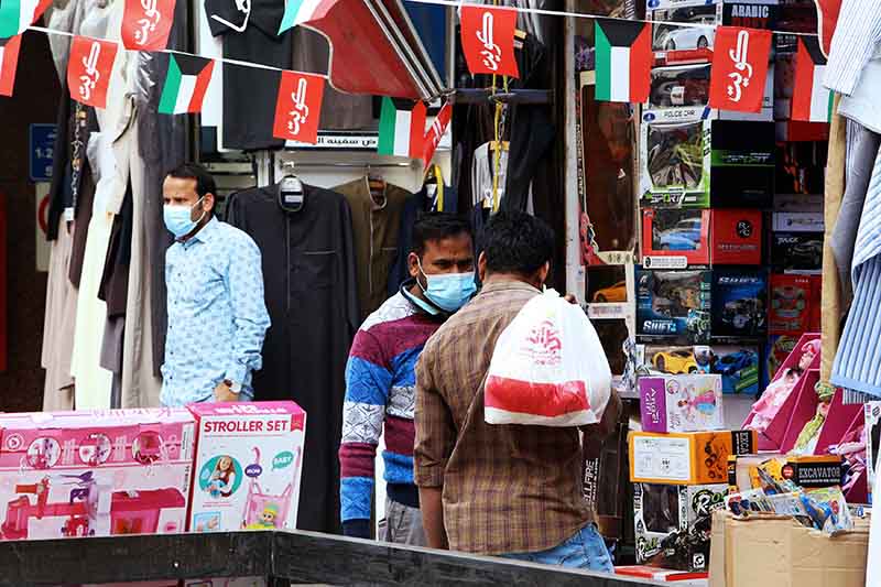 A vendor wearing protective mask speaking with a customer at his shop in Kuwait City on February 26, 2020.