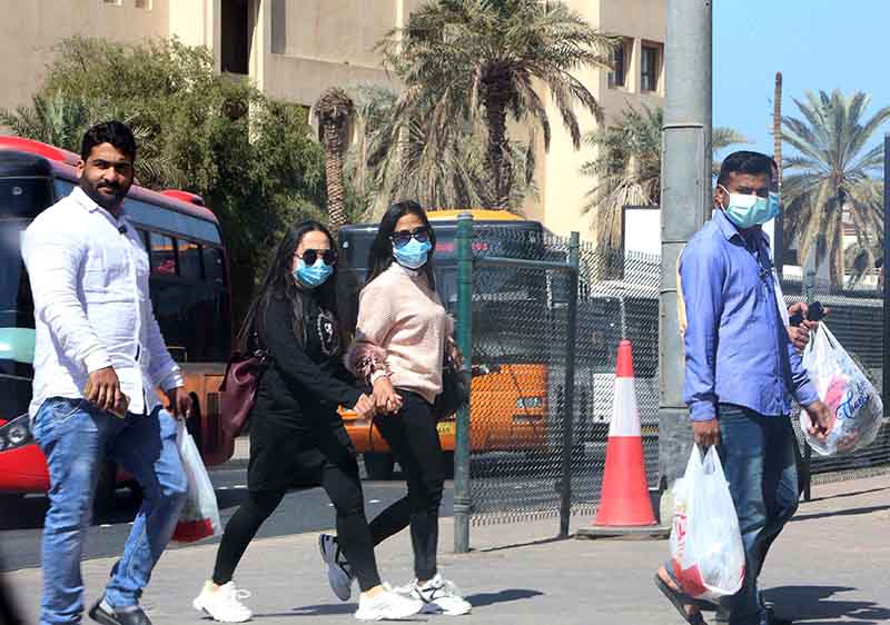 People cross the street wearing protective masks, in Kuwait City on February 27, 2020.