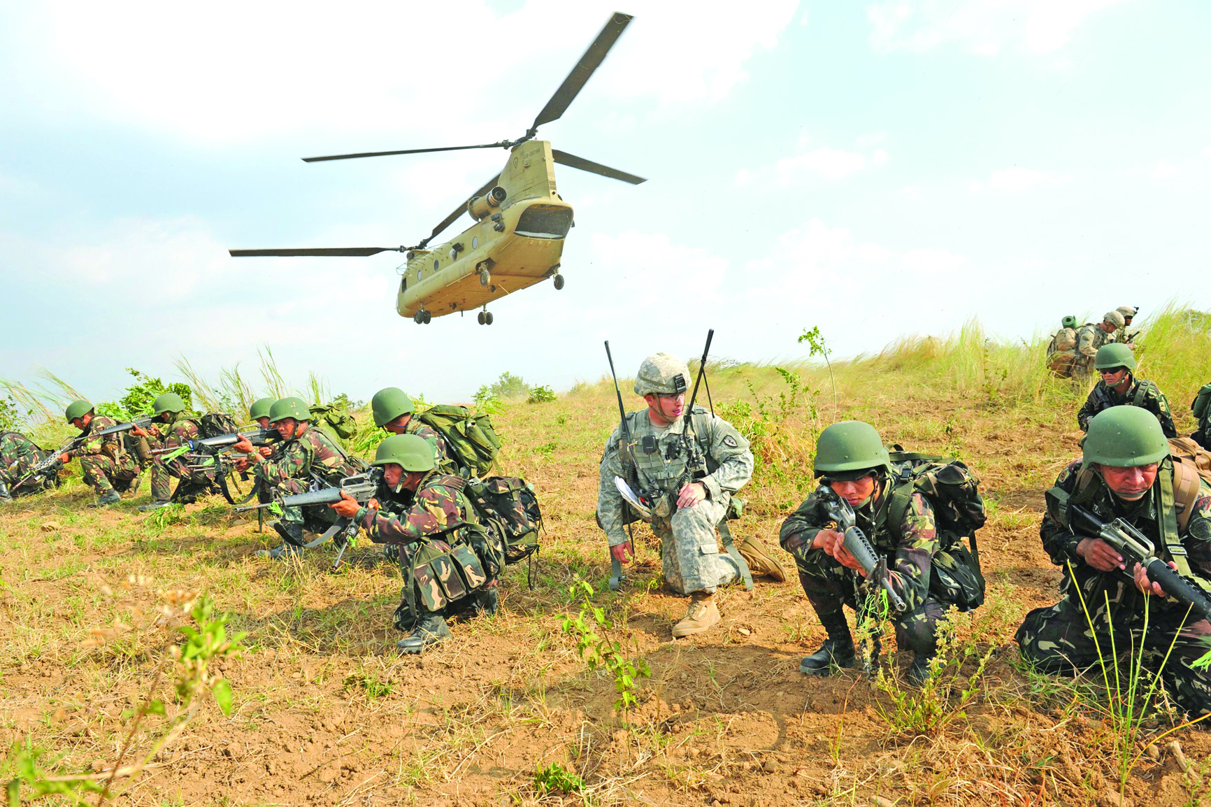 (FILES) This file photo taken on April 20, 2015 shows Philippine soldiers and a US Army soldier from the 2nd Stryker Brigade Combat unit of the 5th Infantry Division based in Hawaii taking their positions after disembarking from a C-47 Chinook helicopter during an air assault exercise inside the military training camp at Fort Magsaysay in Nueva Ecija province. - The Philippines told the US on February 11, 2020 it was quitting a pact key to their historical military alliance, which triggers a six-month countdown to the deal's termination, Manila said. (Photo by TED ALJIBE / AFP)