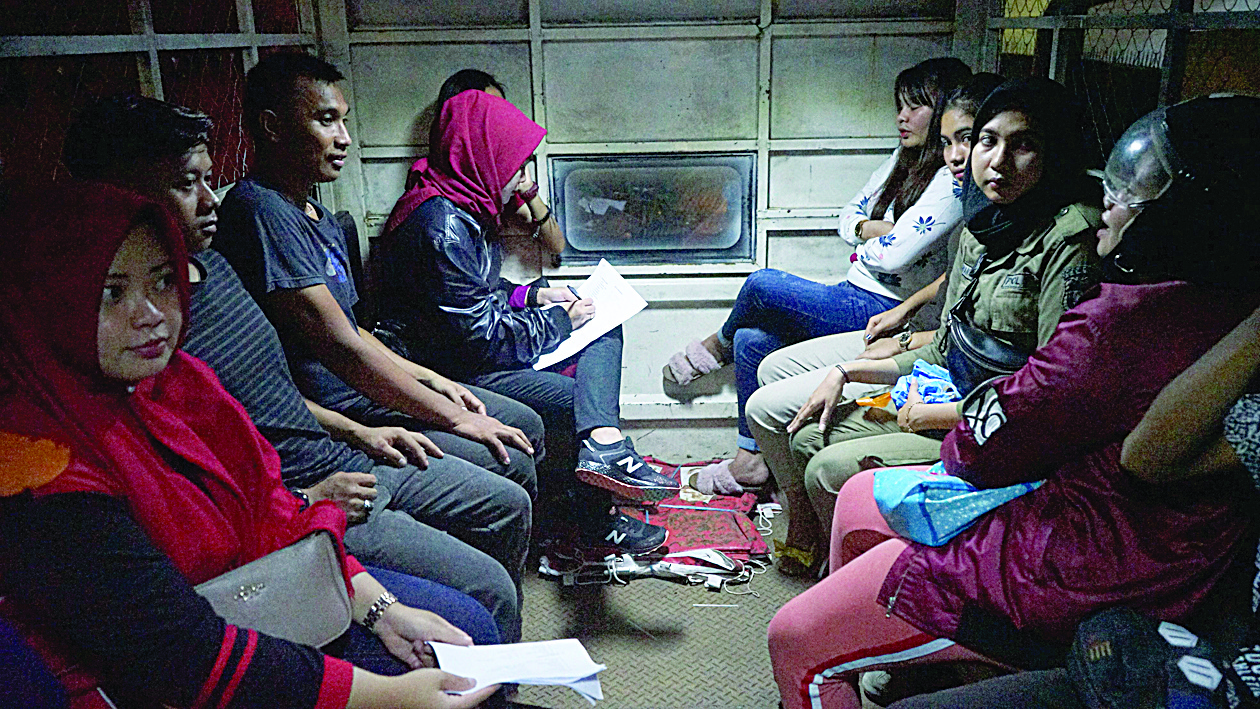 This picture taken on late February 13, 2020 shows a group of people detained during a raid at a hotel in Makassar, where they were caught in the rooms with partners that are not their spouse. - Indonesia wasn't feeling the love for Valentine's Day as authorities arrested frisky couples in one city, scolded stores over prominent condom displays and warned students they would be reprimanded for amorous activities. (Photo by DAENG MANSUR / AFP)