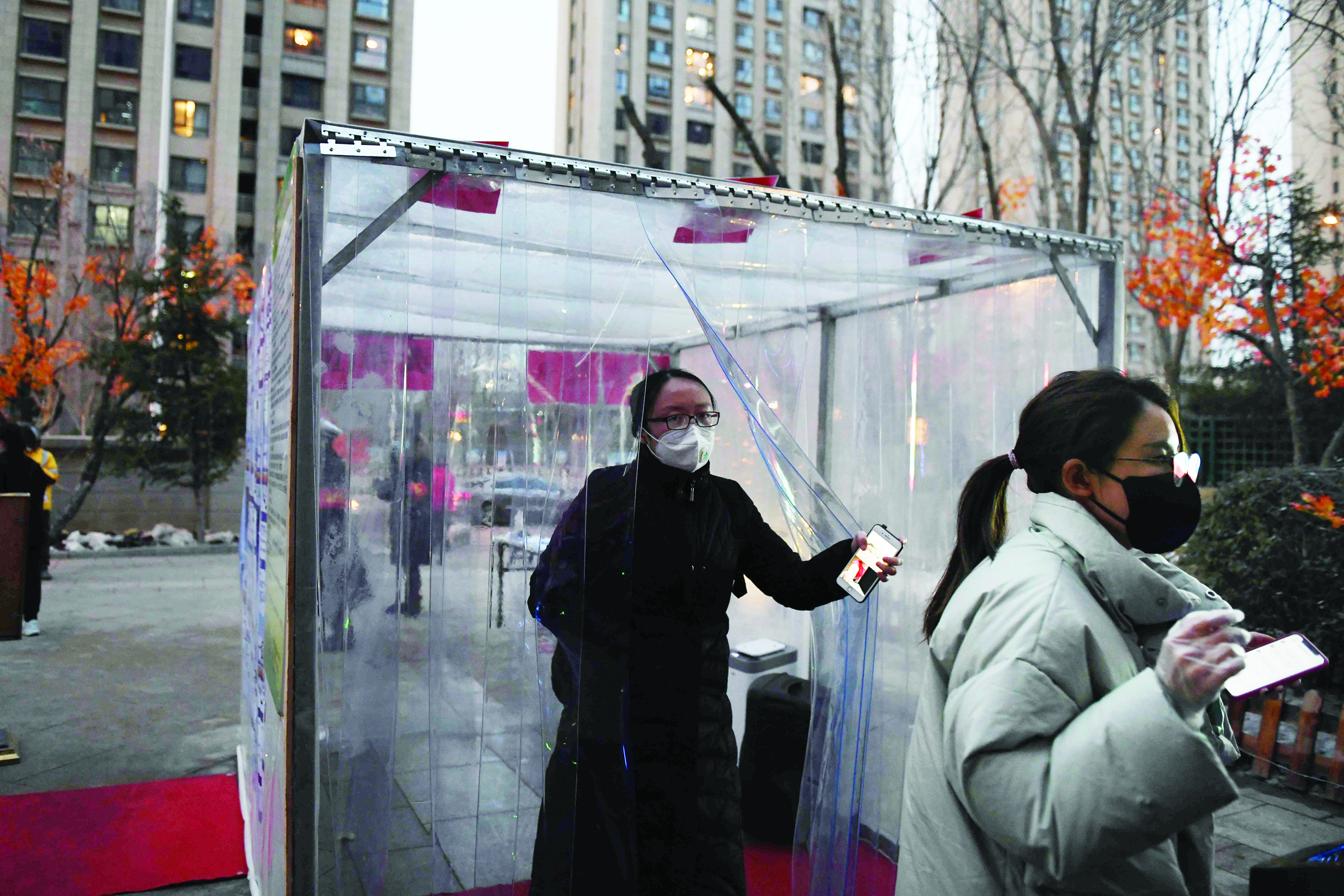 Residents emerge from a disinfection channel set up as a protective measure against the COVID-19 coronavirus at the entrance to their compound in Tongzhou, east of Beijing on February 18, 2020. The channel uses humidifiers to spray a mist of disinfectant as residents pass through. - The toll from China's coronavirus epidemic jumped to 1,868 on February 18 after 98 more people died, according to the National Health Commission. (Photo by GREG BAKER / AFP)