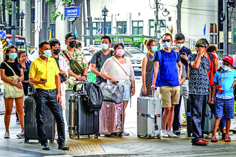 People with protective facemasks wait at a crossroad in downtown Bangkok on February 3, 2020. - Thailand so far has detected 19 confirmed cases of the novel coronavirus believed to have originated in the central Chinese city of Wuhan, which is under lockdown. (Photo by Mladen ANTONOV / AFP)