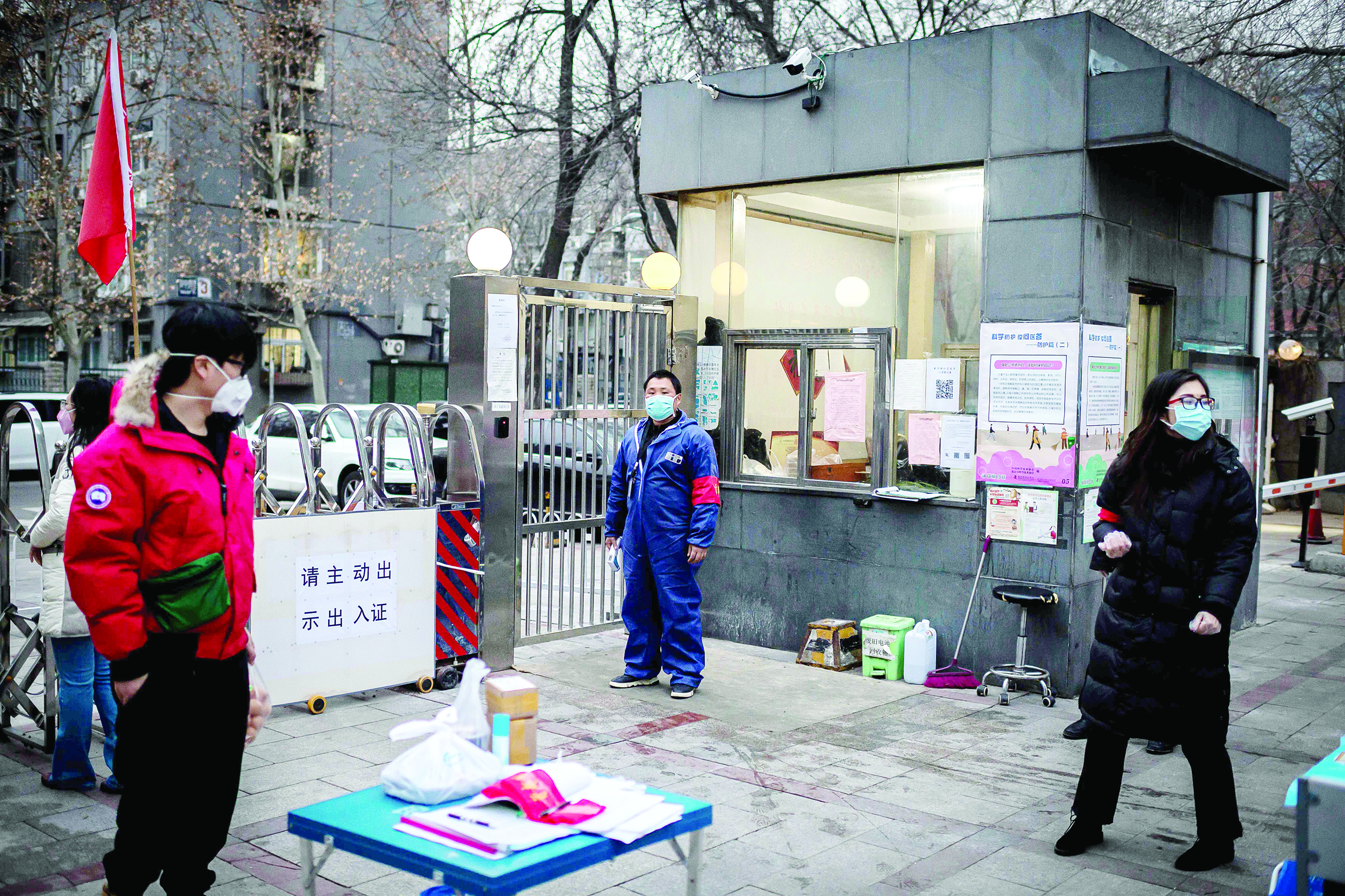 Security officers and residents wearing a protective facemask to protect against the COVID-19 coronavirus stand at the entrance of a residential compound where temperature and special cards access are needed to enter or exit, in Beijing on February 24, 2020. - The novel coronavirus has spread to more than 25 countries since it emerged in December and is causing mounting alarm due to new outbreaks in Europe, the Middle East and Asia. (Photo by NICOLAS ASFOURI / AFP)