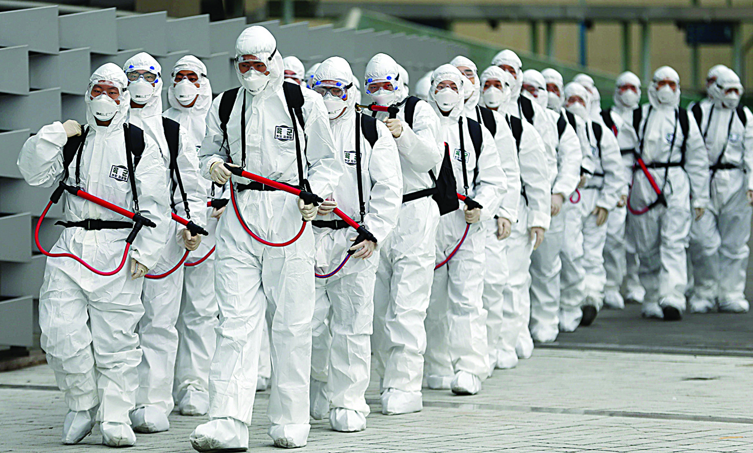 TOPSHOT - South Korean soldiers wearing protective gear move to spray disinfectant as part of preventive measures against the spread of the COVID-19 coronavirus, at Dongdaegu railway station in Daegu on February 29, 2020. - South Korea confirmed 594 more coronavirus cases on February 29, the biggest increase to date for the country and taking the national total to 2,931 infections with three additional deaths. (Photo by - / YONHAP / AFP) / - South Korea OUT / REPUBLIC OF KOREA OUT  NO ARCHIVES  RESTRICTED TO SUBSCRIPTION USE