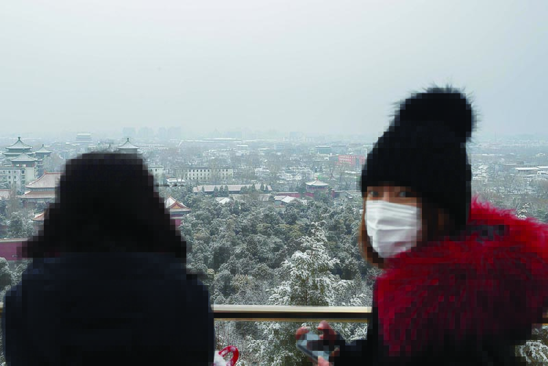 A woman (R) wears a protective mask to prevent the spread of the SARS-like virus as she looks at a view from a hill at the Jingshan park in Beijing on February 2, 2020. - A virus similar to the SARS pathogen has killed more than 300 people in China and spread around the world since emerging in a market in the central Chinese city of Wuhan. (Photo by NICOLAS ASFOURI / AFP)