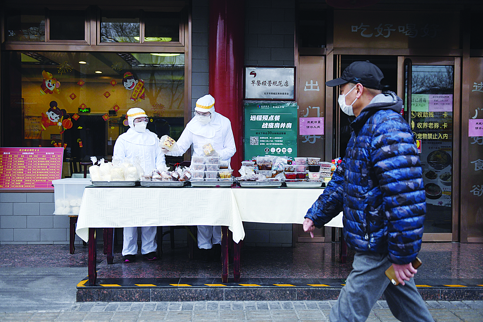 Restaurant workers wear protective clothing as they prepare food to sell on the street outside their restaurant in Beijing on February 20, 2020. - China on February 20 touted a big drop in new virus infections as proof its epidemic control efforts are working, but the toll grew abroad with deaths in Japan and South Korea. (Photo by Greg Baker / AFP)