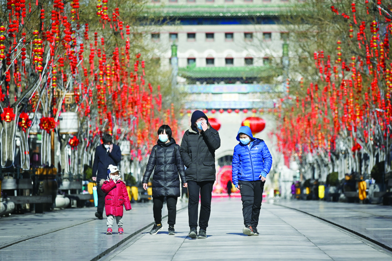 People wearing masks walk along a business street in Beijing on February 4, 2020. - The number of total infections in China's coronavirus outbreak has passed 20,400 nationwide with 3,235 new cases confirmed, the National Health Commission said on February 4. (Photo by WANG Zhao / AFP)