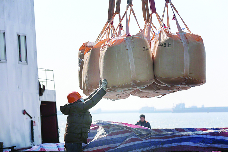 A worker wearing a protective facemask transfers bags of chemical fertilizer that will be exported at a port in Nantong in China's eastern Jiangsu province on January 31, 2020, during the virus outbreak in Hubei's city of Wuhan. - China's manufacturing activity slipped in January, official data showed on January 31, 2020, as the country grapples with a new virus that has claimed more than 200 lives. (Photo by STR / AFP) / China OUT