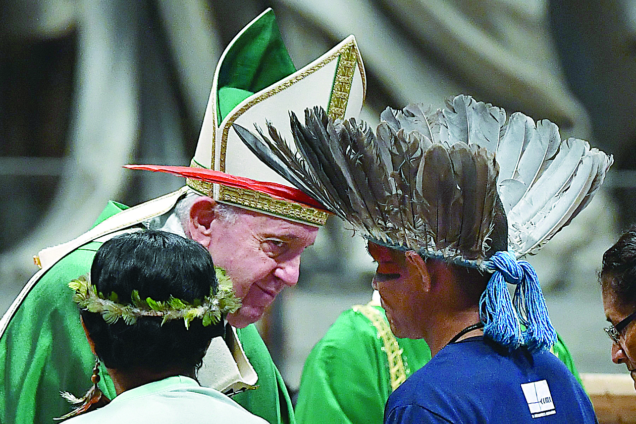 (FILES) In this file photo taken on October 06, 2019 representatives of one of the Amazon Rainforest's ethnic groups (Front) take part in Pope Francis' (L) mass at St. Peter's Basilica in the Vatican, for the opening of the Special Assembly of the Synod of Bishops for the Pan-Amazon Region. - In a highly anticipated text, Pope Francis on February 12, 2020 pleaded for social justice and environmental respect for the Amazon basin, but failed to recommend the controversial idea of married priests. (Photo by Tiziana FABI / AFP)