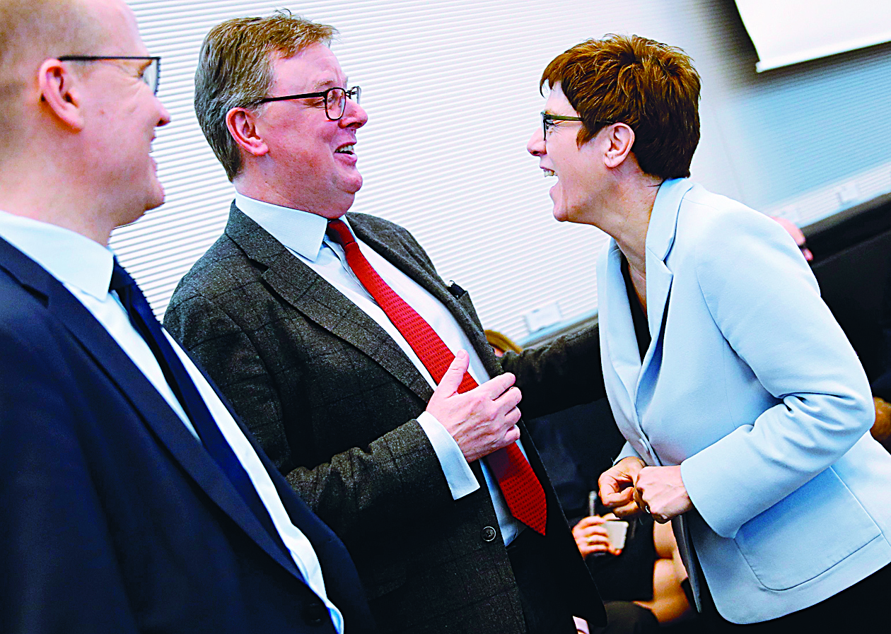 Annegret Kramp-Karrenbauer (R), leader of the conservative Christian Democratic Union party, shares a laugh with parliamentary manager Michael Grosse-Broemer (C) and CDU/CSU parliamentary group leader Ralph Brinkhaus as she arrives for a meeting with the CDU/CSU parliamentary group at the Bundestag (lower house of parliament) in Berlin on February 11, 2020. (Photo by Odd ANDERSEN / AFP)