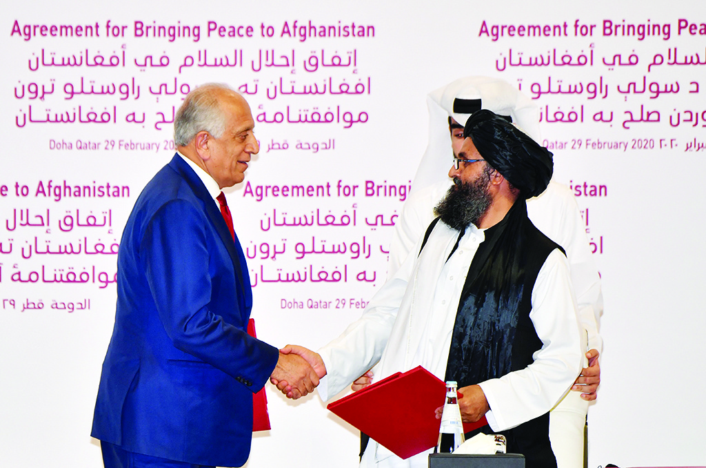 TOPSHOT - (L to R) US Special Representative for Afghanistan Reconciliation Zalmay Khalilzad and Taliban co-founder Mullah Abdul Ghani Baradar shake hands after signing a peace agreement during a ceremony in the Qatari capital Doha on February 29, 2020 - The United States signed a landmark deal with the Taliban, laying out a timetable for a full troop withdrawal from Afghanistan within 14 months as it seeks an exit from its longest-ever war. (Photo by Giuseppe CACACE / AFP)