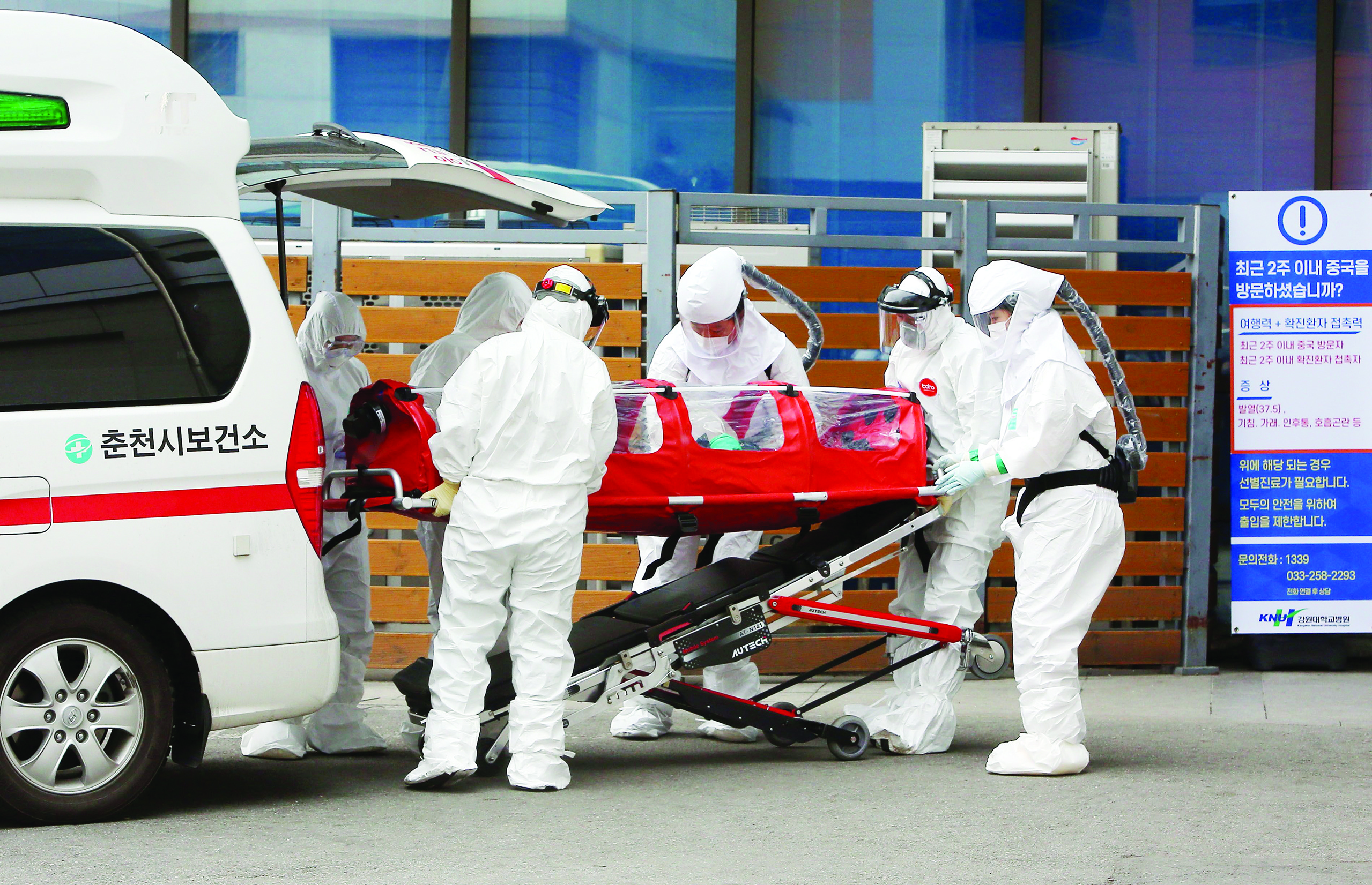 TOPSHOT - Medical workers wearing protective gear carry a patient infected with the COVID-19 coronavirus at a hospital in Chuncheon on February 22, 2020. - South Korea reported 142 more coronavirus cases on February 22, the sharpest spike in infections yet, with more than half of the new cases linked to a hospital in a southern city. The national toll of 346 is now the second-highest outside of China. (Photo by - / YONHAP / AFP) / - South Korea OUT / REPUBLIC OF KOREA OUT  NO ARCHIVES  RESTRICTED TO SUBSCRIPTION USE