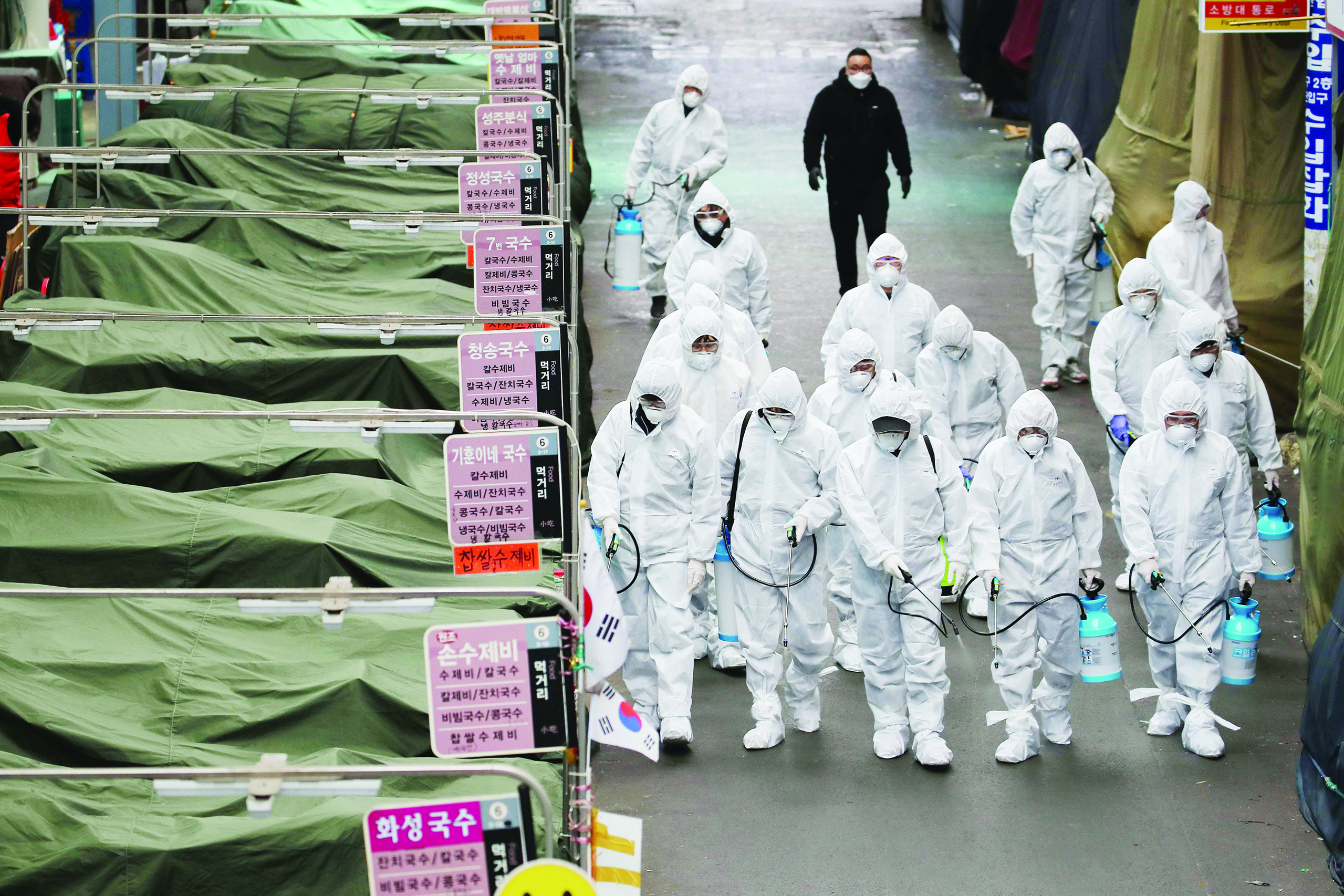 TOPSHOT - Market workers wearing protective gear spray disinfectant at a market in the southeastern city of Daegu on February 23, 2020 as a preventive measure after the COVID-19 coronavirus outbreak. - South Korea reported two additional deaths from coronavirus and 123 more cases on February 23, with nearly two thirds of the new patients connected to a religious sect. The national toll of 556 cases is now the second-highest outside of China. (Photo by - / YONHAP / AFP) / - South Korea OUT / REPUBLIC OF KOREA OUT  NO ARCHIVES  RESTRICTED TO SUBSCRIPTION USE