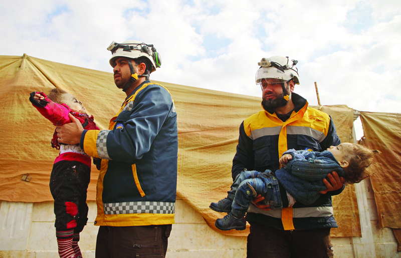 TOPSHOT - EDITORS NOTE: Graphic content / Members of a Syrian civil defence team, known as the White Helmets, prepare the bodies of children, among nine civilians killed in an air strike in the rebel-held northern Aleppo province, for burial in a collective grave in the village of Urum al-Kubra on February 3, 2020, following one of the deadliest rounds of bombardment since an ongoing government offensive against the area started last month. (Photo by AAREF WATAD / AFP)