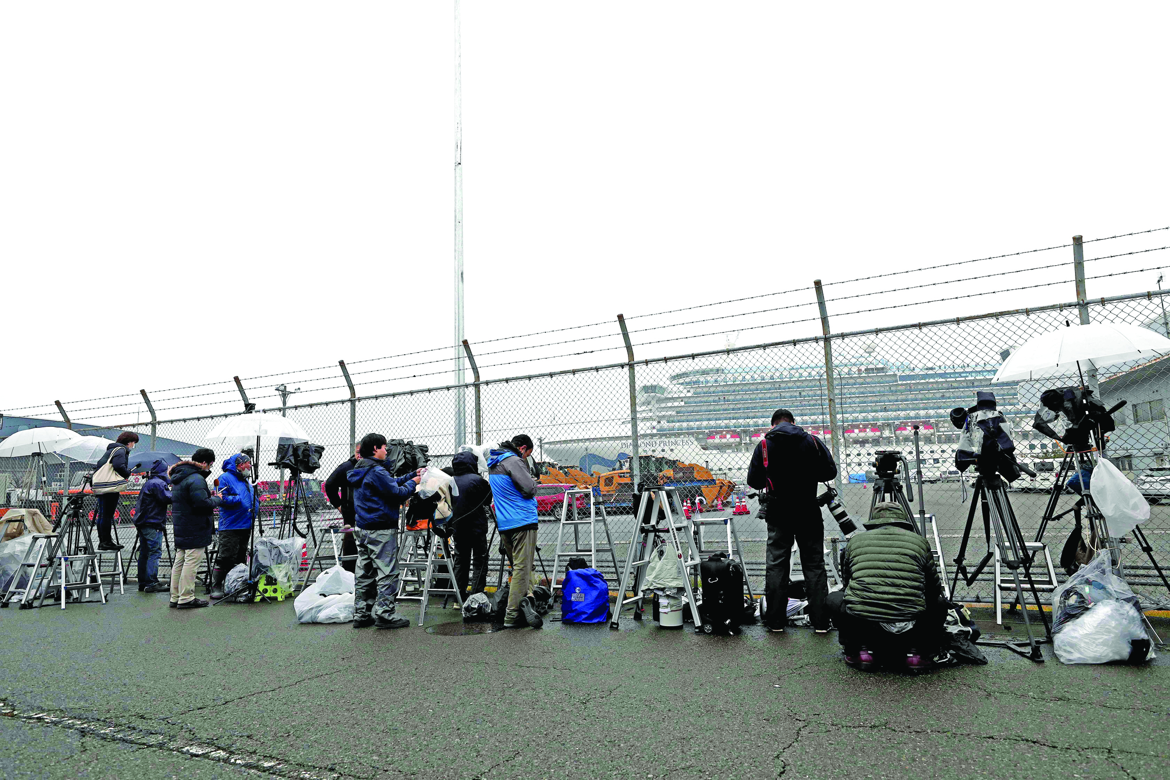 Members of the media wait near the Diamond Princess cruise ship, with people quarantined onboard due to fears of the new COVID-19 coronavirus, at the Daikaku Pier Cruise Terminal in Yokohama port on February 16, 2020. - The number of people who have tested positive for the new coronavirus on a quarantined ship off Japan's coast has risen to 355, the country's health minister said. (Photo by Behrouz MEHRI / AFP)