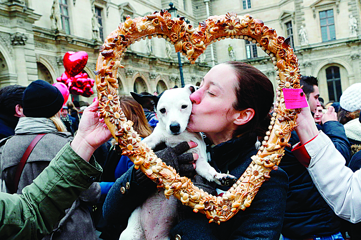 (FILES) In this file photo a woman kisses her dog while posing behind a heart-shaped pastry during a flashmob in Paris on February 14, 2014, to mark the launch of the website Wikilove.com, an online encyclopedia of love. - The idea that animals can experience love was once anathema to the psychologists who studied them, seen as a case of putting sentimentality before scientific rigor. (Photo by FRANCOIS GUILLOT / AFP)