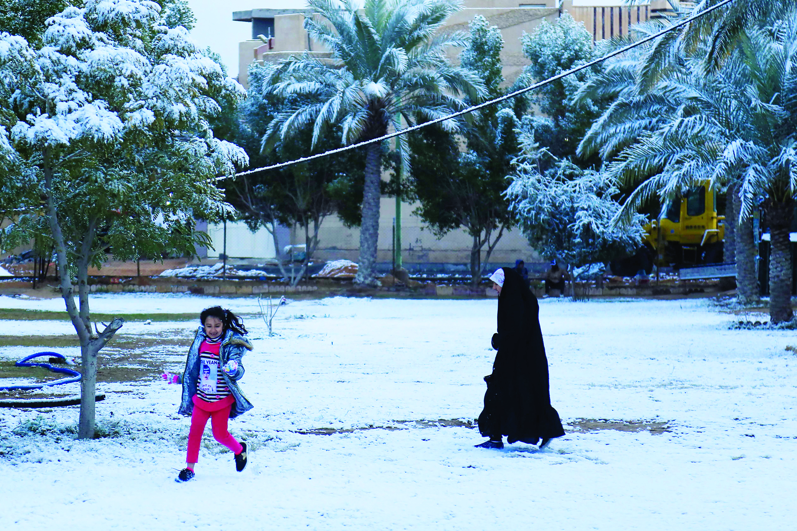 An Iraqi girl plays with her mother in the snow in the holy Shiite city of Karbala on February 11, 2020. - Iraq's capital Baghdad woke up covered in a thin layer of fresh snow, an extremely rare phenomenon for one of the world's hottest countries. Snow also covered the Shiite holy city of Karbala further south and Mosul in the north, where heavier precipitation left a blanket of snow over the city's centuries-old ruins. (Photo by Atta KENARE / AFP)