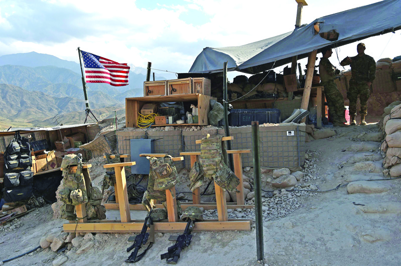 (FILES) In this file photograph taken on July 7, 2018, US Army soldiers from NATO look on as U.S. flag flies at a checkpoint during a patrol against Islamic State militants at the Deh Bala district in the eastern province of Nangarhar Province. - Two American troops were killed and six others wounded when an Afghan soldier armed with a machine gun opened fire, the US military confirmed on February 9. (Photo by WAKIL KOHSAR / AFP)