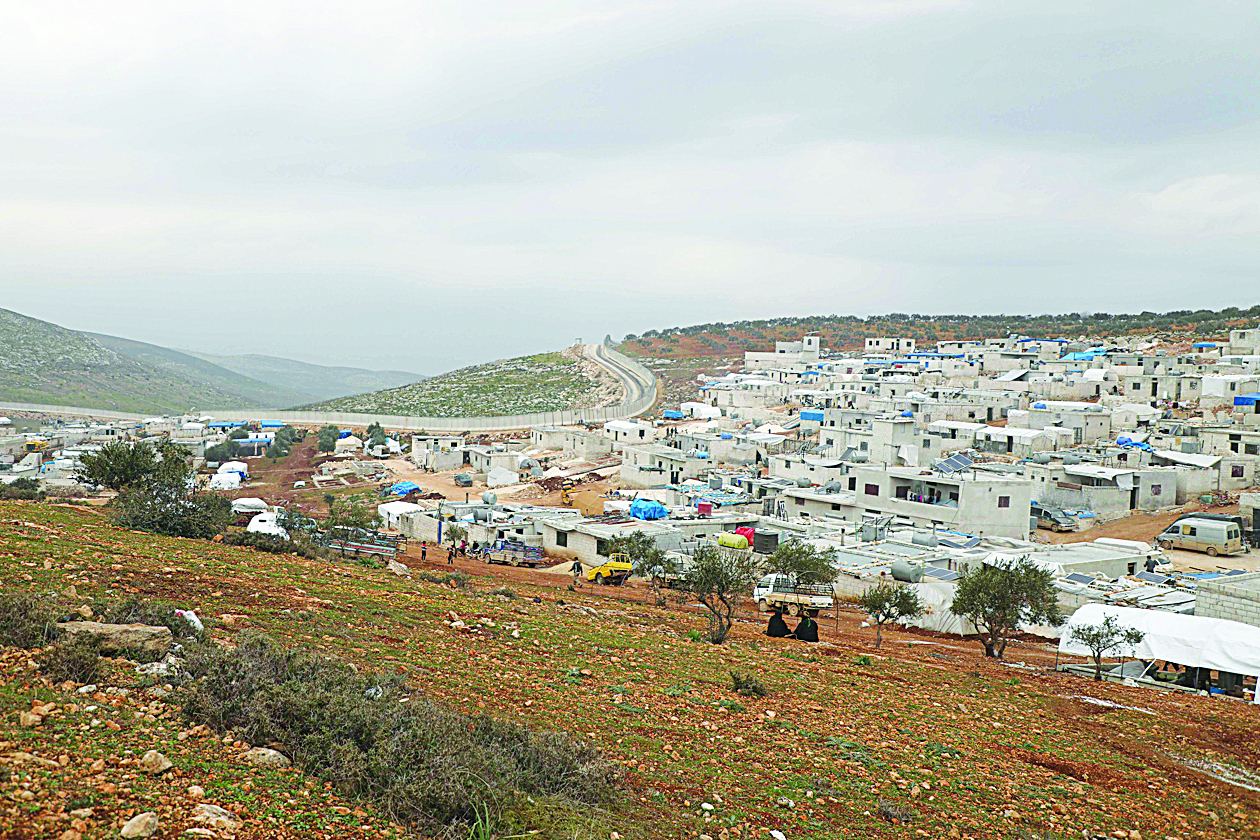 A picture taken on February 21, 2020 shows makeshift homes at an informal camp for the displaced in Kafr Lusin village on the border with Turkey in Syria's northwestern province of Idlib. - Six months ago, the family fled deadly fighting in Idlib province of northwest Syria, seeking shelter near the border village of Kafr Lusin, where dozens of families live in an informal camp for the displaced. Turkey, which already hosts the world's largest number of Syrian refugees with around 3.6 million people, has placed barbed wire and watchtowers along the wall to prevent any more crossings. (Photo by AAREF WATAD / AFP)