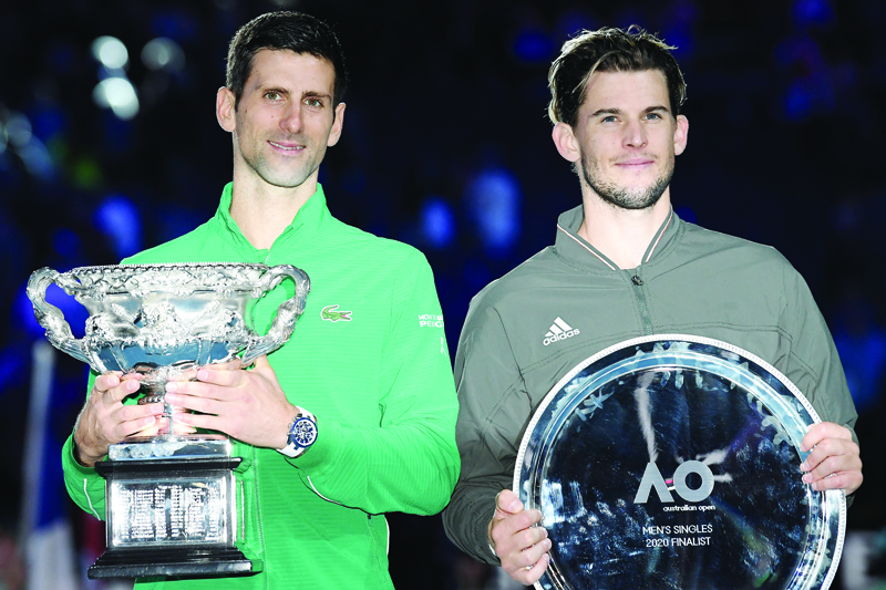Serbia's Novak Djokovic holds the Norman Brookes Challenge Cup trophy after beating Austria's Dominic Thiem (R) in their men's singles final match on day fourteen of the Australian Open tennis tournament in Melbourne on February 3, 2020. (Photo by Saeed KHAN / AFP) / IMAGE RESTRICTED TO EDITORIAL USE - STRICTLY NO COMMERCIAL USE