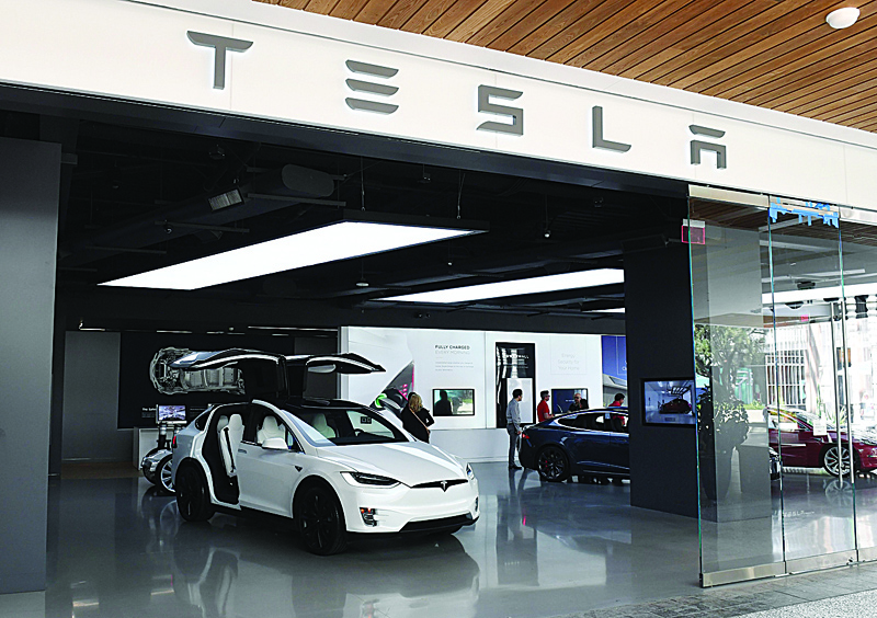 (FILES) In this file photo taken on April 25, 2019 People stand in a Tesla showroom at a shopping mall in Los Angeles. - Tesla shares dived around 20 percent in early afternoon trading on February 5, 2020, giving back some of the gains the electric-car maker racked up since October. Shares stood at $723.92, down 18.3 percent around 1835 GMT, reversing a nearly unbroken trend over the last four months that accelerated this week when the stock jumped more than 36 percent in a two-day surge. (Photo by Mark RALSTON / AFP)