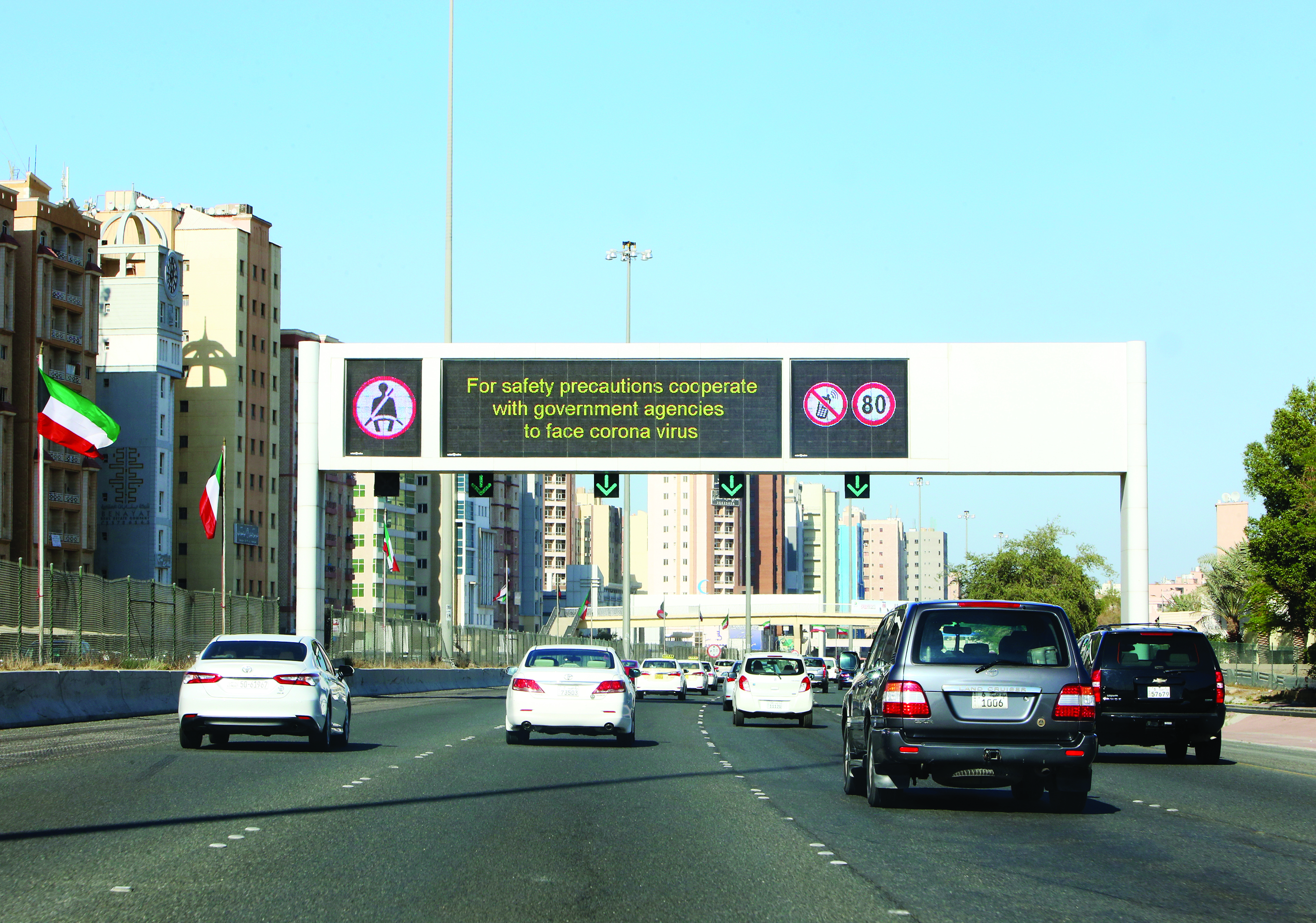 Vehicles pass by a billboard showing precautionary instructions against the coronavirus as they drive on a main highway in Kuwait City on March 3, 2020.