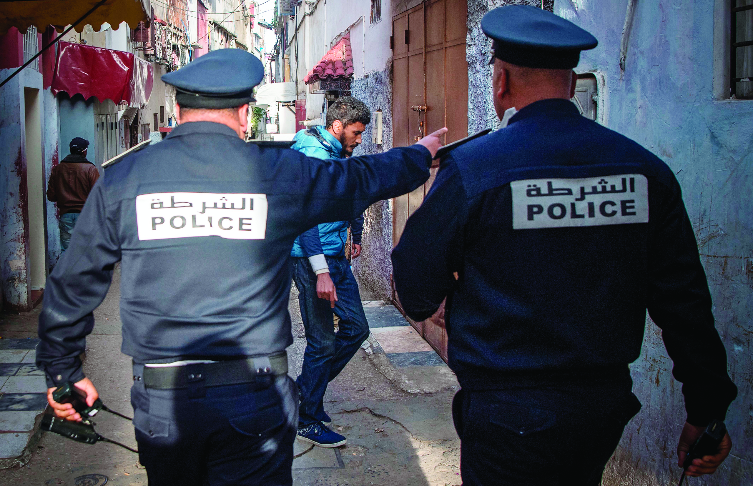 TOPSHOT - Moroccan policemen, patrolling as part of a larger combined security force, instruct people to return to and remain at home as a measure against the COVID-19 coronavirus pandemic in the capital Rabat's district of Takadoum on March 27, 2020. (Photo by FADEL SENNA / AFP)