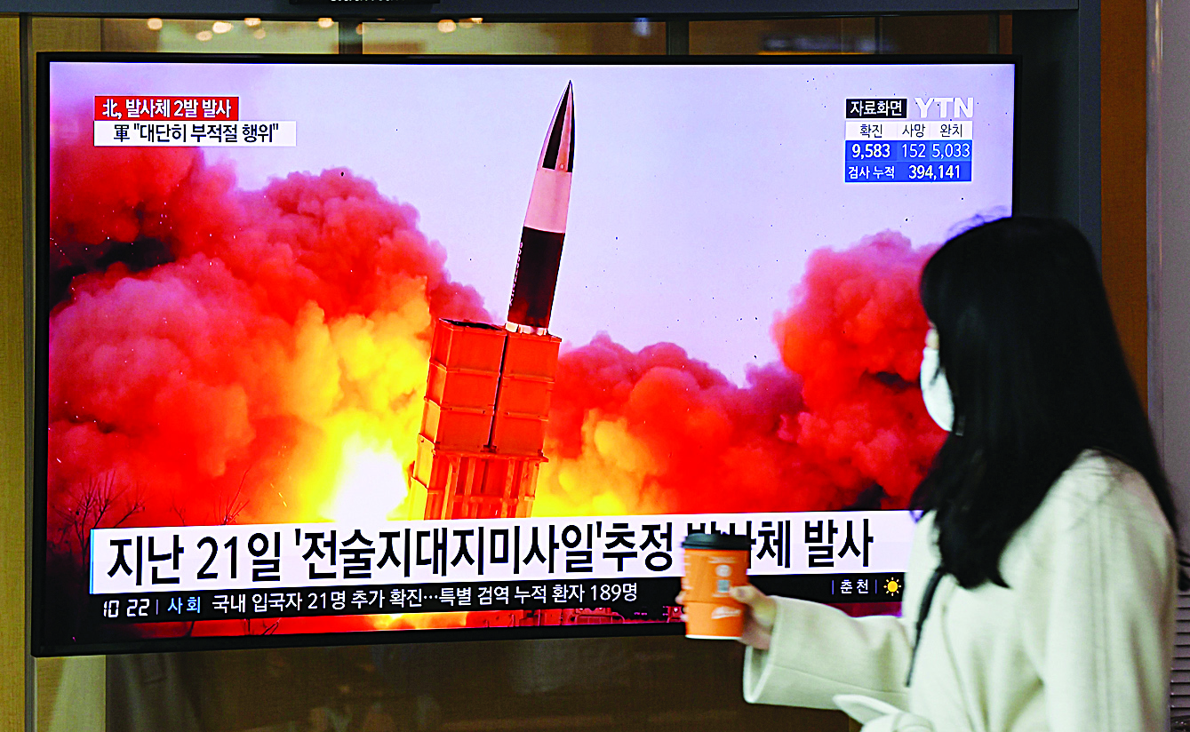 A woman walks past a screen showing file footage of a North Korean missile test, at a railway station in Seoul on March 29, 2020. - North Korea fired what appeared to be two short-range ballistic missiles off its east coast on March 29, the fourth such launch this month as the world battles the coronavirus pandemic. (Photo by Jung Yeon-je / AFP)