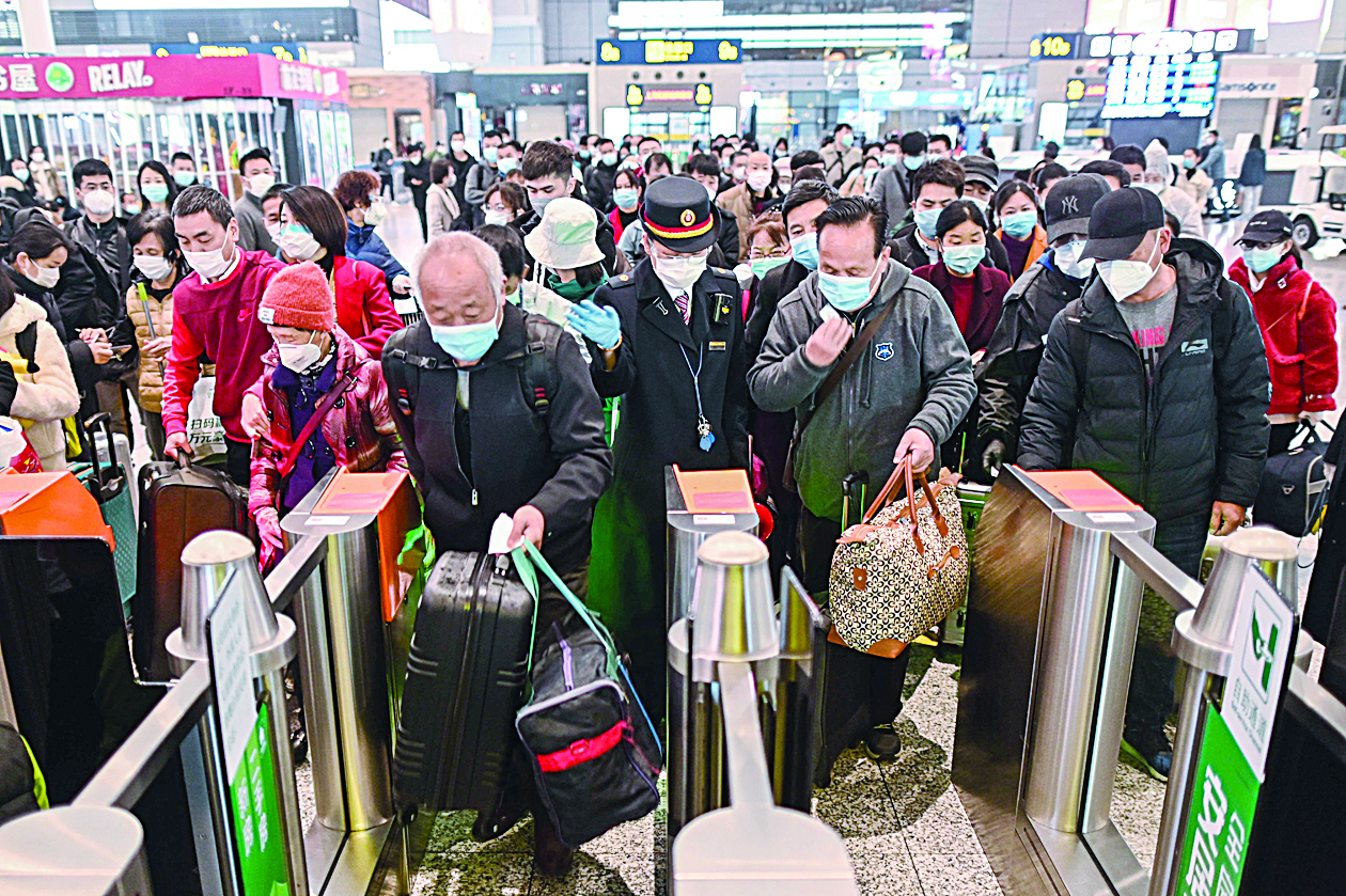 People wearing face masks as a preventive measure against the COVID-19 novel coronavirus walk to a train, one of the stops being Wuhan, at a station in Shanghai on March 28, 2020. - The Chinese city of 11 million people that was Ground Zero for what became the global coronavirus pandemic partly reopened on March 28, after more than two months of almost total isolation. (Photo by Hector RETAMAL / AFP)