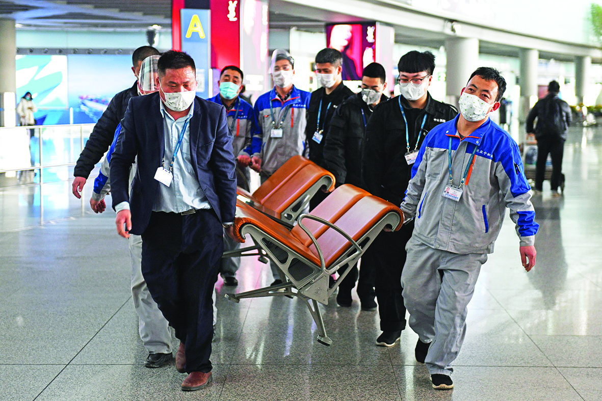 Workers wear face masks as they remove seating from a public area at the Beijing Capital Airport in Beijing on March 5, 2020. - China on March 5 reported 31 more deaths from the new COVID-19 coronavirus epidemic, taking the country's overall toll past 3,000, with the number of new infections slightly increasing. (Photo by GREG BAKER / AFP)