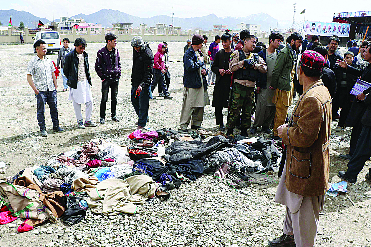Men stand next to a pile of clothes and footwear of the victims, a day after a gun attack at a political rally in Kabul on March 7, 2020. - Dozens of people were killed when gunmen opened fire at a political rally in Kabul on March 6, the deadliest assault in Afghanistan since the US signed a withdrawal deal with the Taliban. (Photo by STR / AFP)