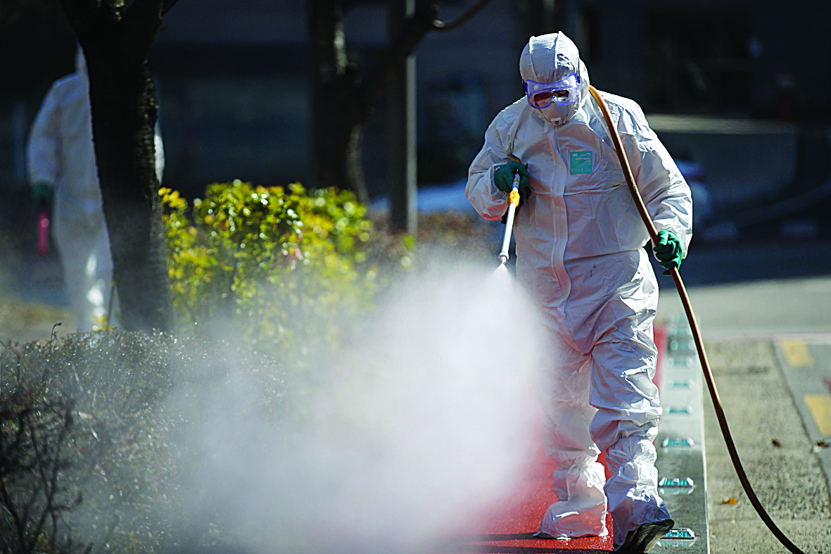 A worker wearing protective gear sprays disinfectant on the street to help prevent the spread of the COVID-19 coronavirus, near a hospital in Seoul on March 11, 2020. - South Korea announced its first rise in new coronavirus cases for five days on March 11, following a run of declines that have raised hopes the outbreak is coming under control. A total of 242 infections were confirmed on March 10 taking the South's total to 7,755. (Photo by - / YONHAP / AFP) / - South Korea OUT / REPUBLIC OF KOREA OUT  NO ARCHIVES  RESTRICTED TO SUBSCRIPTION USE