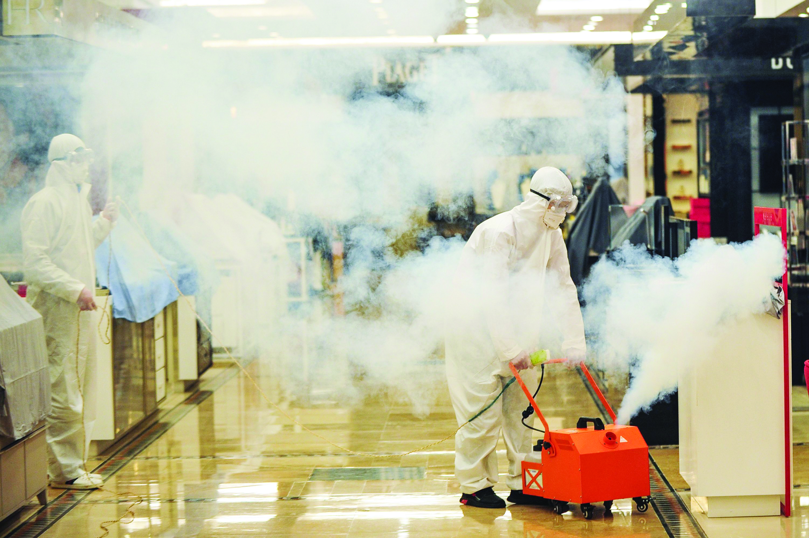 This photo taken on March 29, 2020 shows staff members spraying disinfectant at a shopping mall as it prepares to reopen to the public after closing due to the COVID-19 coronavirus outbreak in Wuhan in China's central Hubei province. - Wuhan, the central Chinese city where the coronavirus first emerged last year, partly reopened on March 28 after more than two months of near total isolation for its population of 11 million. (Photo by STR / AFP) / China OUT