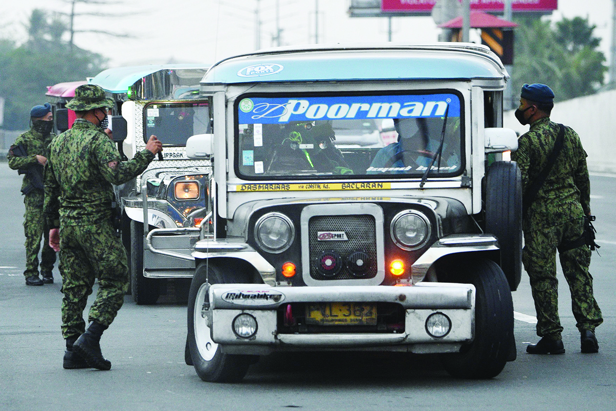 Philippine police personnel man a checkpoint bordering nearby Cavite province and suburban Las Pinas in Manila on March 15, 2020, as the government steps up efforts to curb the spread of the new coronavirus. - Police began closing off access to the Philippines' sprawling and densely populated capital Manila on March 15, imposing a quarantine that officials hope will curb the nation's rising number of coronavirus cases. (Photo by Ted ALJIBE / AFP)