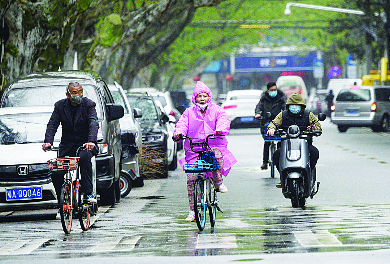 People wearing face masks ride along a street in Wuhan, in China's central Hubei province on March 29, 2020. (Photo by NOEL CELIS / AFP)