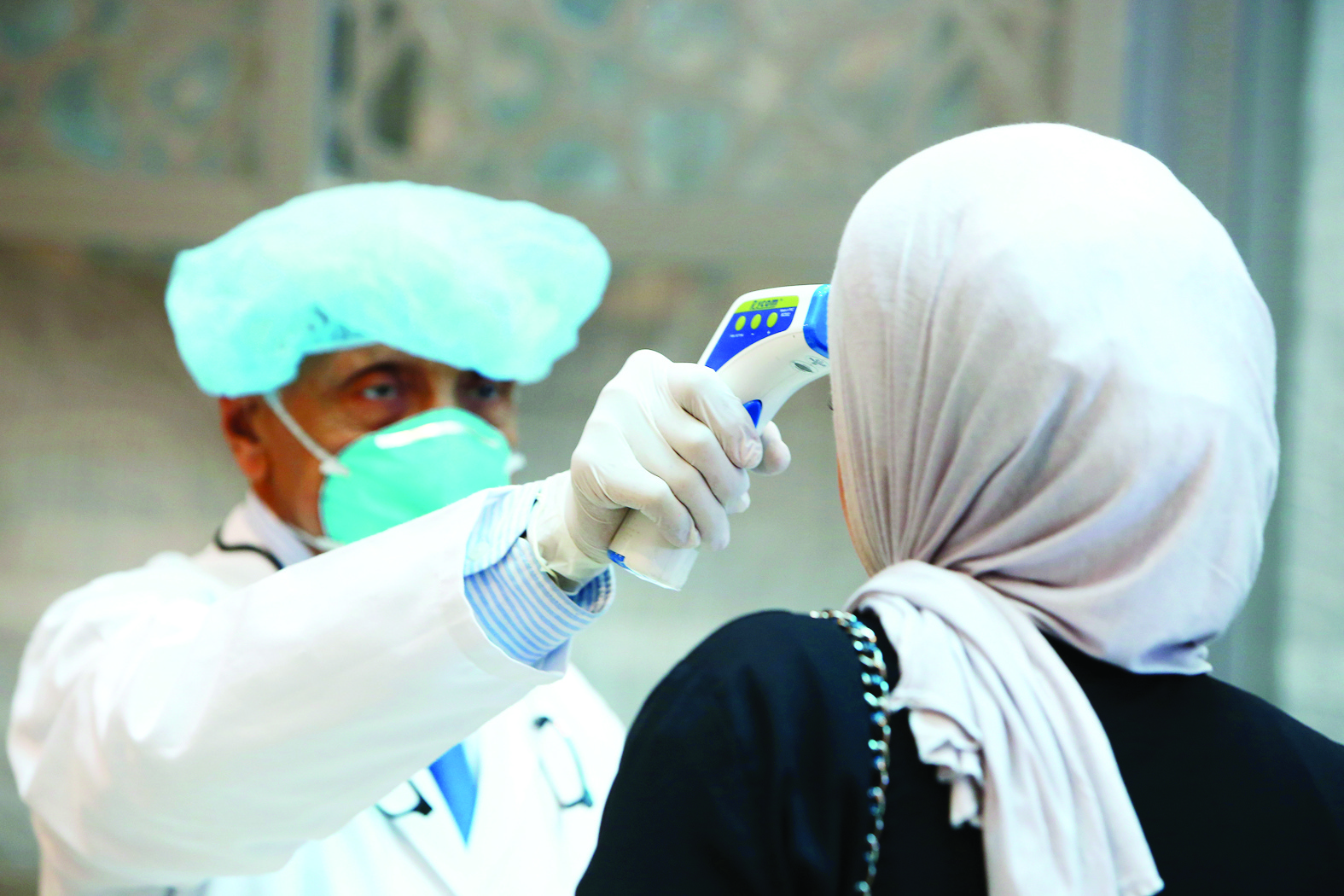 Kuwait health ministry workers scan employee of the ministries complex, as she arrive to her work, in Kuwait City on March 3, 2020.