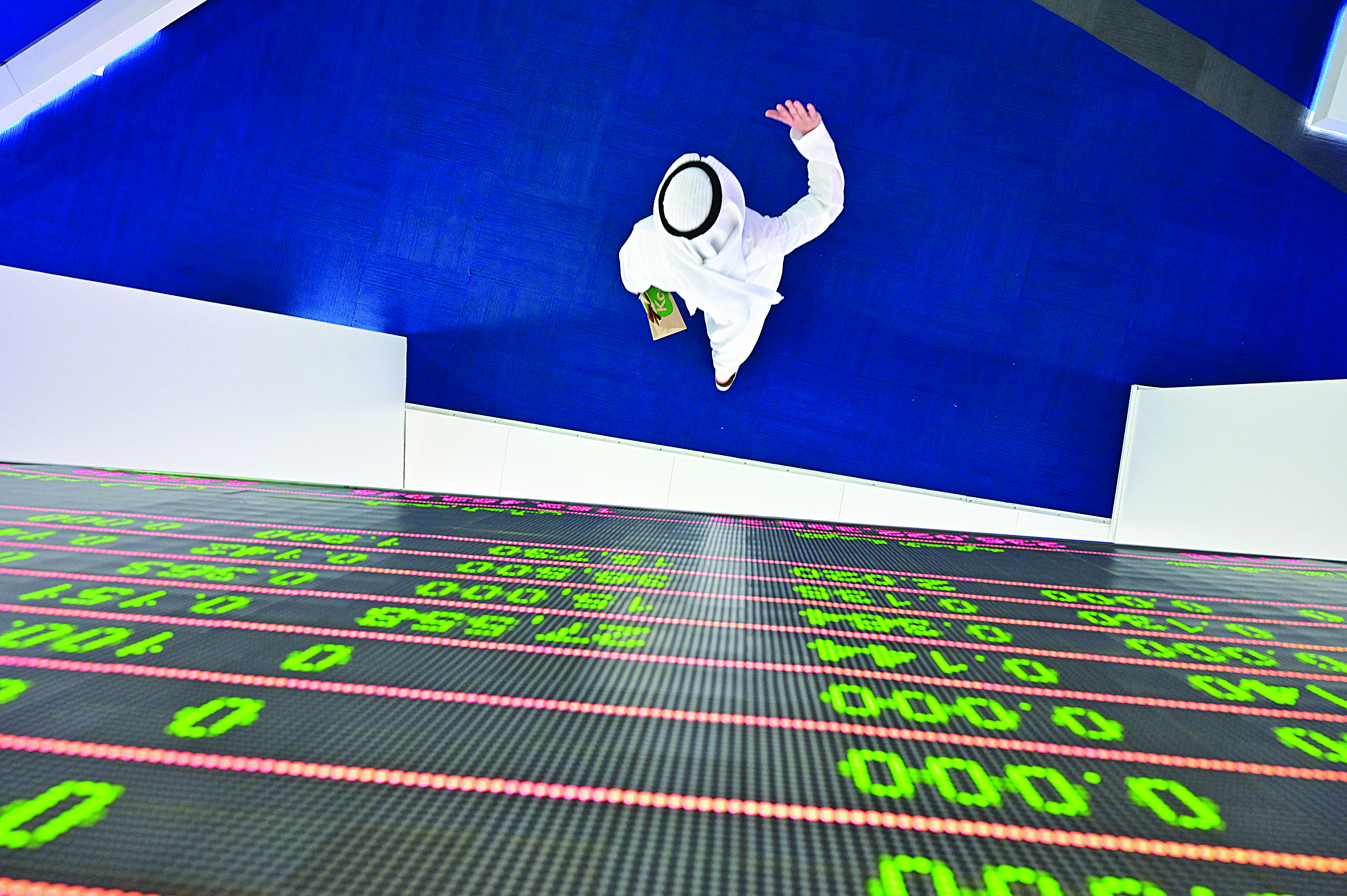 A trader walks by beneath a stock display board at the Dubai Stock Exchange in the United Arab Emirates, on March 8, 2020. - Saudi's stock exchange fell 6.5 percent and other Gulf markets tumbled to multi-year lows at the start of trading after OPEC and its allies failed to clinch a deal over oil production cuts. (Photo by GIUSEPPE CACACE / AFP)
