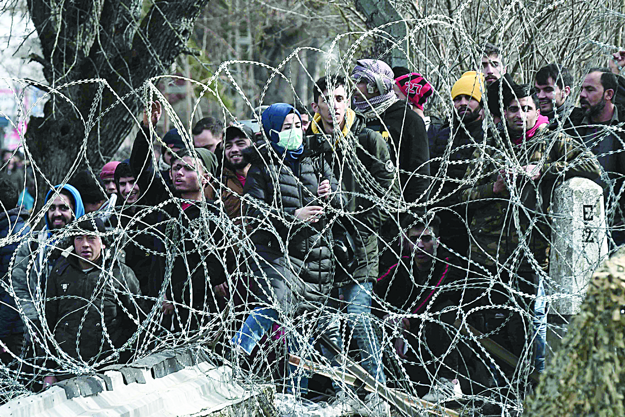 This picture taken from the Greek side of the Greece-Turkey border near Kastanies, shows migrants waiting on the Turkish side on March 2, 2020. - Greece was on a state of alert on March 1, 2020 as it faced an influx of thousands of migrants seeking to cross the border from Turkey, with locals fearing a new immigration crisis. More than 13,000 migrants have gathered on the Turkish side of the river which runs 200 kilometres (125 miles) along the frontier and separates them from Greece and therefore the European Union. The flow of migrants from Turkey has triggered EU fears of a re-run of the 2015 migrant emergency when Greece became the main EU entry point for a million migrants, most of them refugees fleeing the Syrian civil war. (Photo by Sakis MITROLIDIS / AFP)