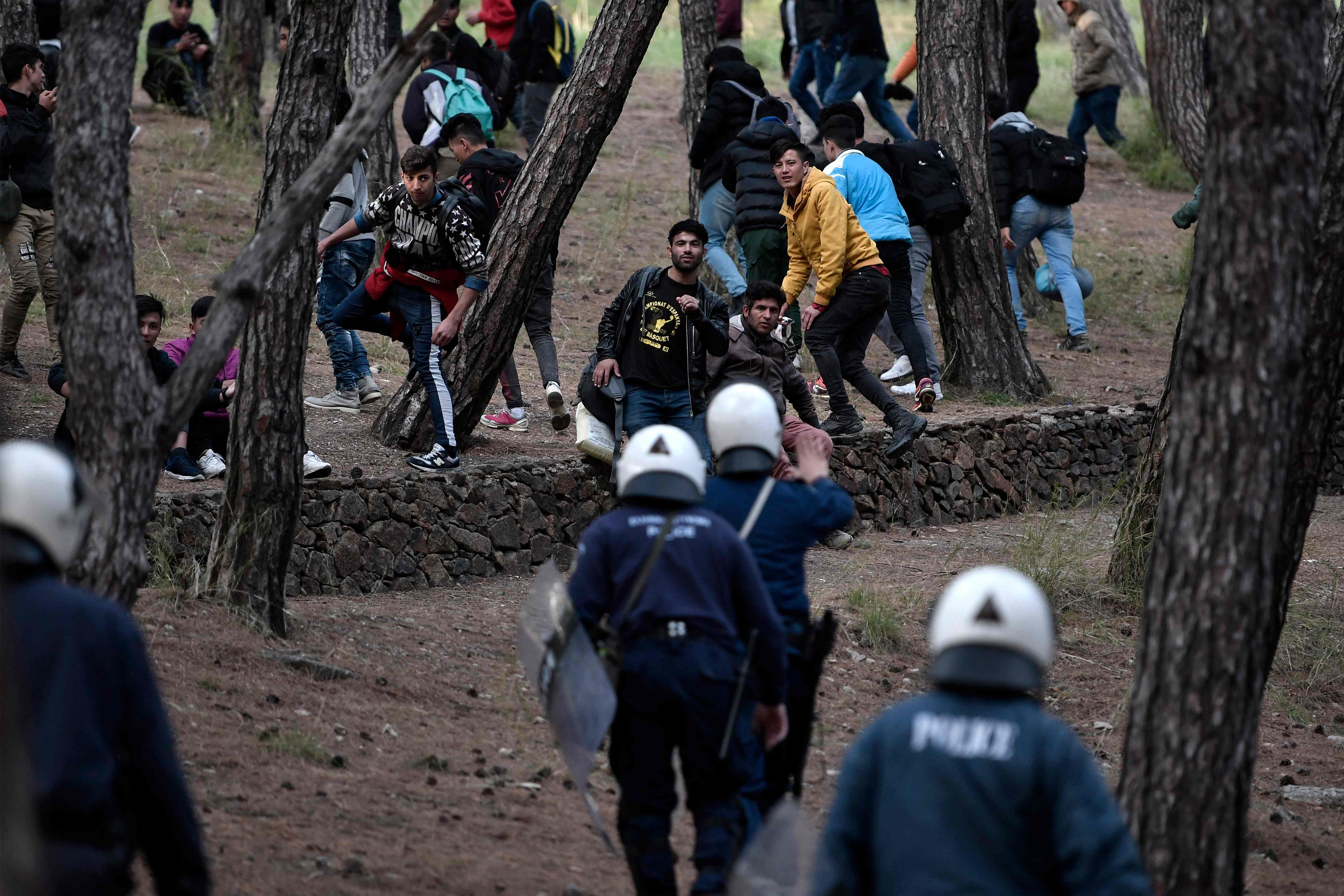 TOPSHOT - Migrants run from riot police after being pushed to go back to Moria camp from the port of Mytilene, on the island of Lesbos, where they were hoping to get on a ferry to Athens on March 3, 2020. - Several aid groups on Greece's Lesbos said they were suspending work with refugees and evacuating staff on March 3 in the wake of violence and threats, as tensions soar on an island in the crosshairs of the migrant crisis. EU chiefs pledged millions of euros of financial assistance to Greece to help tackle the migration surge. (Photo by LOUISA GOULIAMAKI / AFP)