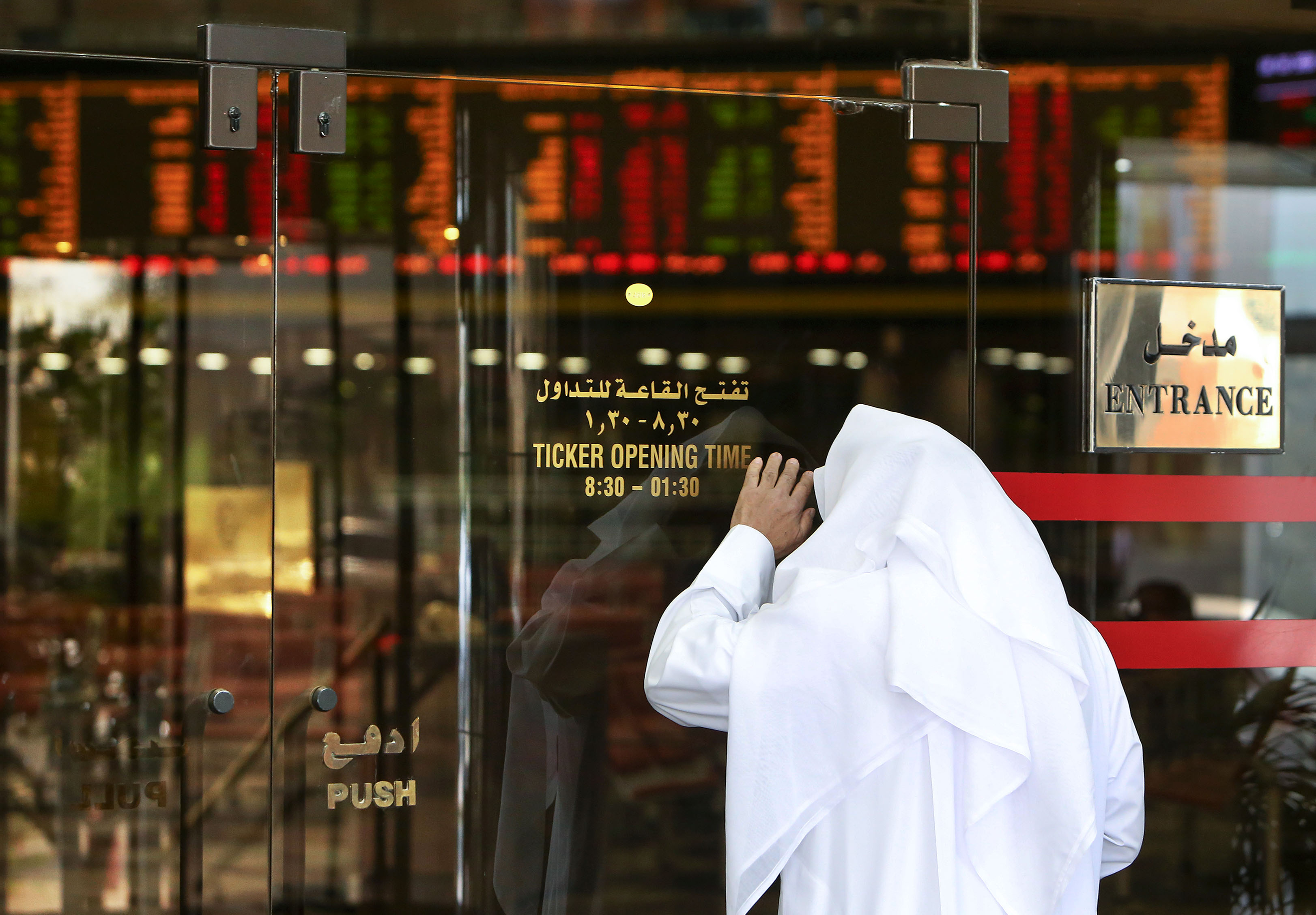 A Kuwaiti trader checks stock prices from the outside after authorities stopped trading at Boursa Kuwait in Kuwait City, on March 8, 2020. - Kuwait Boursa authorities stopped trading after the Premier Index slumped 10 percent while the All-Shares index dived 8.4 percent, as shares in the energy-dependent Gulf plunged to multi-year lows after OPEC's failure to agree on a coronavirus action plan prompted fears of an all-out oil price war. (Photo by YASSER AL-ZAYYAT / AFP)