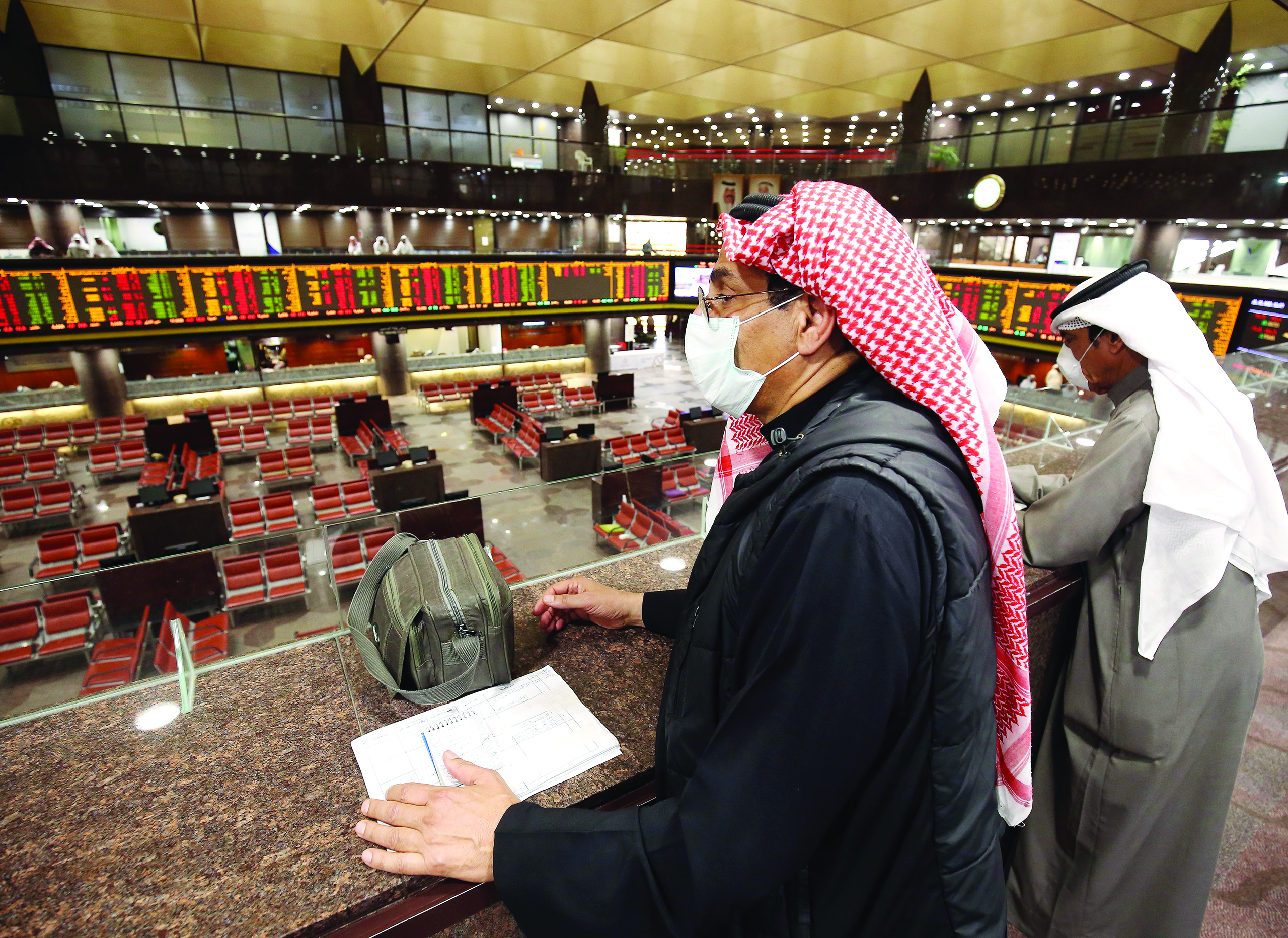 Kuwaiti traders wearing protective masks follow the market at the Boursa Kuwait stock exchange in Kuwait City on March 1, 2020. - Boursa Kuwait decided to close the main trading hall due to the COVID-19 coronavirus disease developments. Stock markets in the oil-rich Gulf states plunged on March 1 over fears of the impact of the coronavirus, which also battered global bourses last week. All of the seven exchanges in the Gulf Cooperation Council (GCC), which were closed the previous two days for the Muslim weekend, were hit as oil prices dropped below $50 a barrel. The region's slide was led by Kuwait Boursa, where the All-Share Index fell 10 percent, triggering its closure. Kuwait's bourse was closed for most of last week for national holidays. (Photo by YASSER AL-ZAYYAT / AFP)