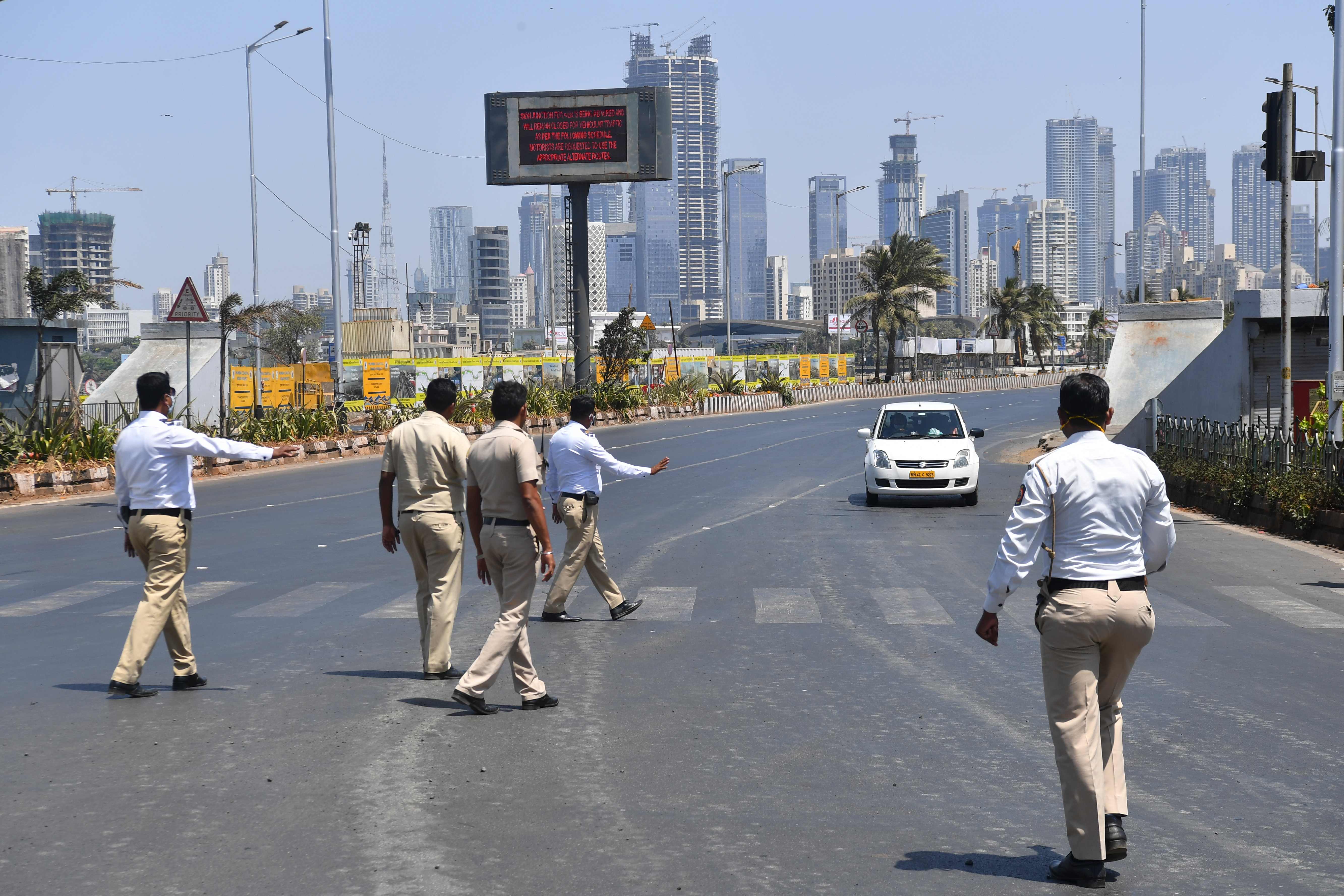 Police personnel prepare to stop a car during a nationwide one-day Janata (civil) curfew imposed as a preventive measure against the COVID-19 coronavirus, in Mumbai on March 22, 2020. - Nearly one billion people around the world were confined to their homes, as the coronavirus death toll crossed 13,000 and factories were shut in worst-hit Italy after another single-day fatalities record. (Photo by INDRANIL MUKHERJEE / AFP)