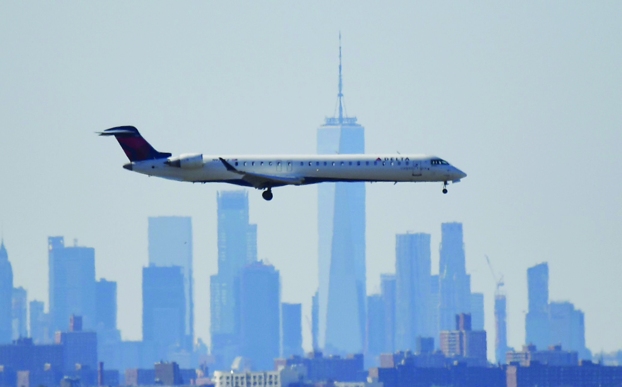 A plane from Delta airline is seen above the skyline of Manhattan before it lands at JFK airport on March 15, 2020 in New York City. - Chaos gripped major US airports Sunday as Americans returning from coronavirus-hit European countries overwhelmed authorities attempting to process the surge.Frustrated passengers complained of hours-long lines, crowded and unsanitary conditions and general disarray in the system for screening people for symptoms of the virus.Chaos gripped major US airports Sunday as Americans returning from coronavirus-hit European countries overwhelmed authorities attempting to process the surge. Frustrated passengers complained of hours-long lines, crowded and unsanitary conditions and general disarray in the system for screening people for symptoms of the virus. Schools, museums, sports arenas and entertainment venues have closed in some states, but St. Patrick's Day celebrations still filled bars and restaurants over the weekend, leading some local officials to consider more extensive shutdowns. (Photo by Johannes EISELE / AFP)