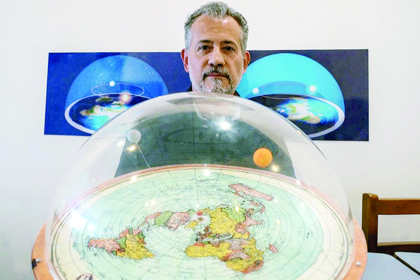 Brazilian self-avowed flat-Earth conspiracy theorist Anderson Neves holds a model of the flat earth surrounded by a dome during an interview with AFP in Sao Paulo, Brazil, on February 13, 2020. - Eleven million people in Brazil, 7% of its population, believe that the Earth is flat, according to Datafolha polling institute. (Photo by Florence GOISNARD / AFP)