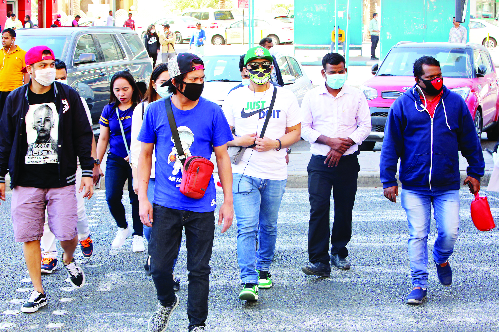 People wearing protective masks cross the street in Kuwait City on March 2, 2020, amid a global outbreak of the novel Coronavirus. (Photo by YASSER AL-ZAYYAT / AFP)
