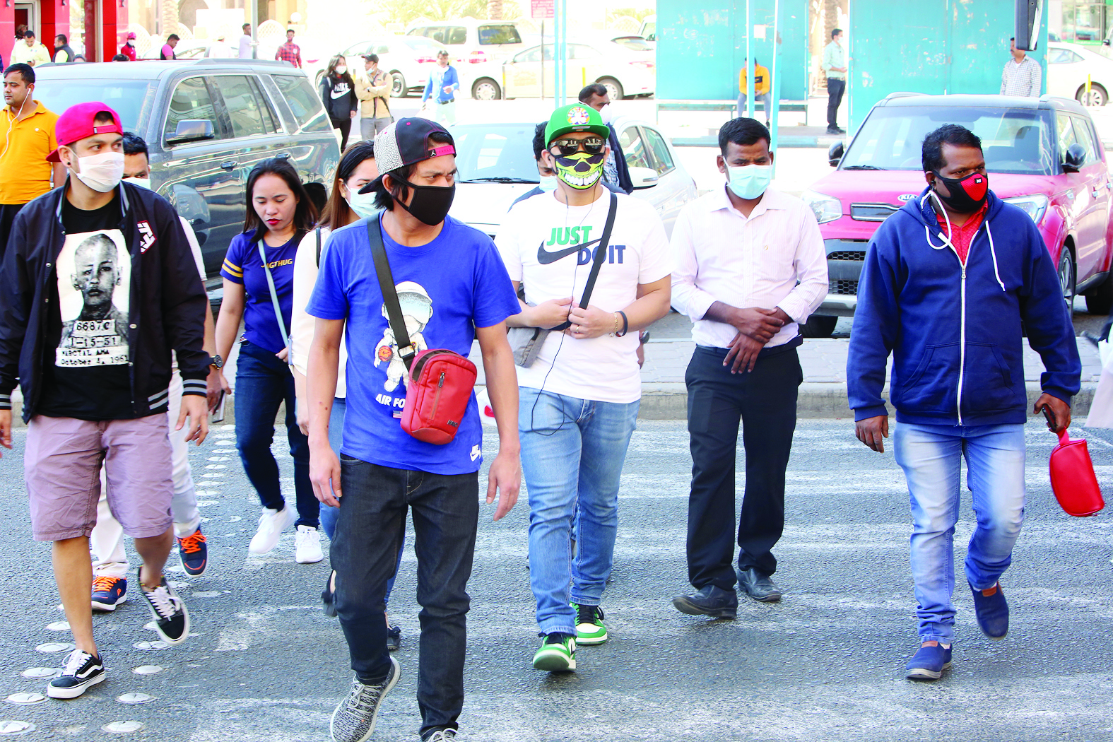 People wearing protective masks as they cross the street in Kuwait City on March 2, 2020. Kuwait announed ten more infections in Coronavirus, for the total of 56 cases.