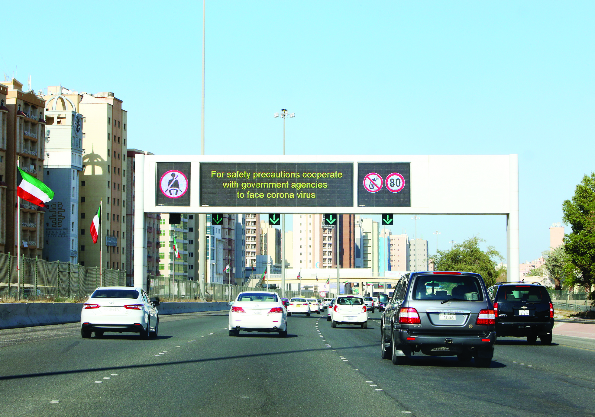 Vehicles pass by a billboard showing precautionary instructions against the coronavirus as they drive on a main highway in Kuwait City on March 3, 2020.