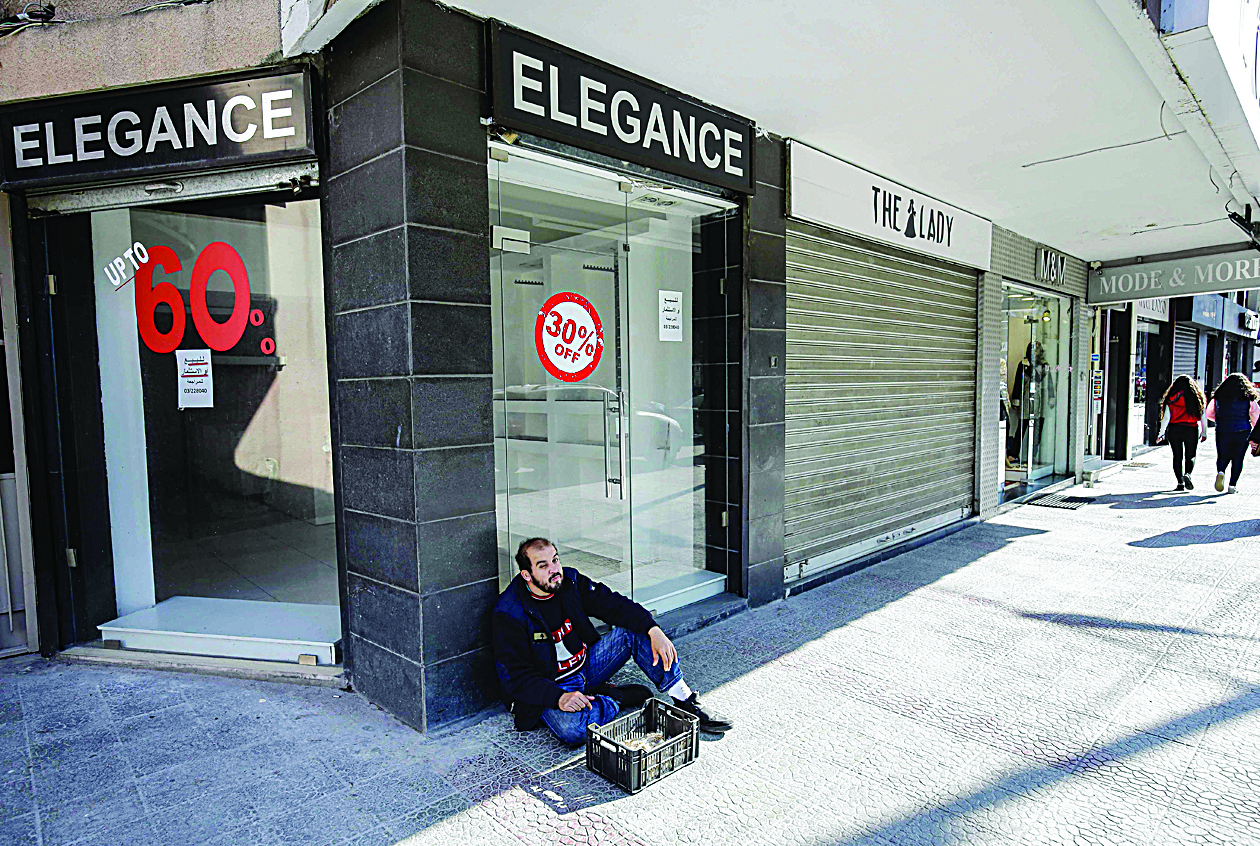 A Lebanese man sits next to a closed store in the northern city of Tripoli on February 25, 2020. (Photo by Ibrahim CHALHOUB / AFP)